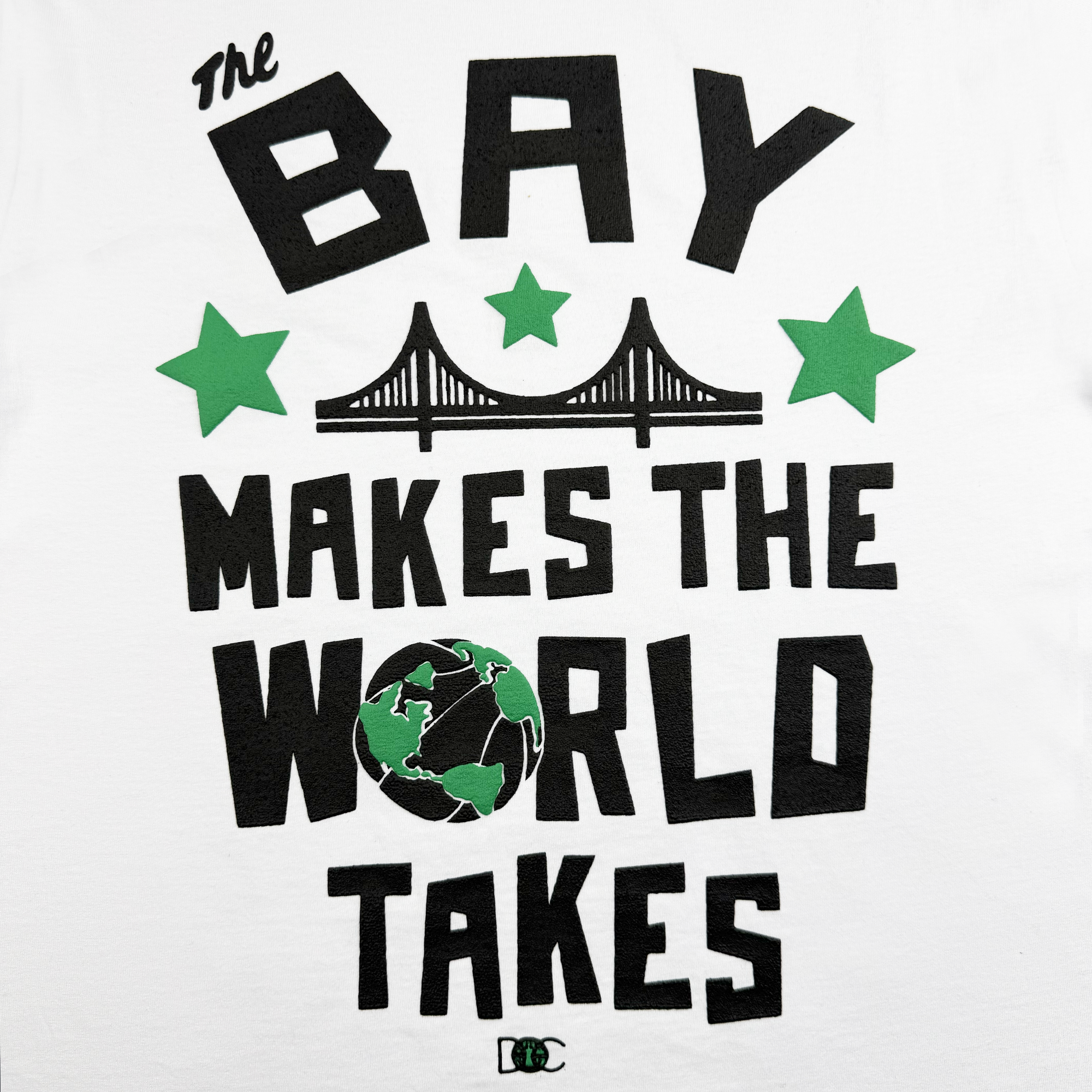 The Bay Bridge Tee by Oaklandish features "The Bay Makes The World Takes" in stylized black letters with green stars and a globe, symbolizing the Bay Area's global vibe. Above the text is a simple bridge illustration, all set against a white background.