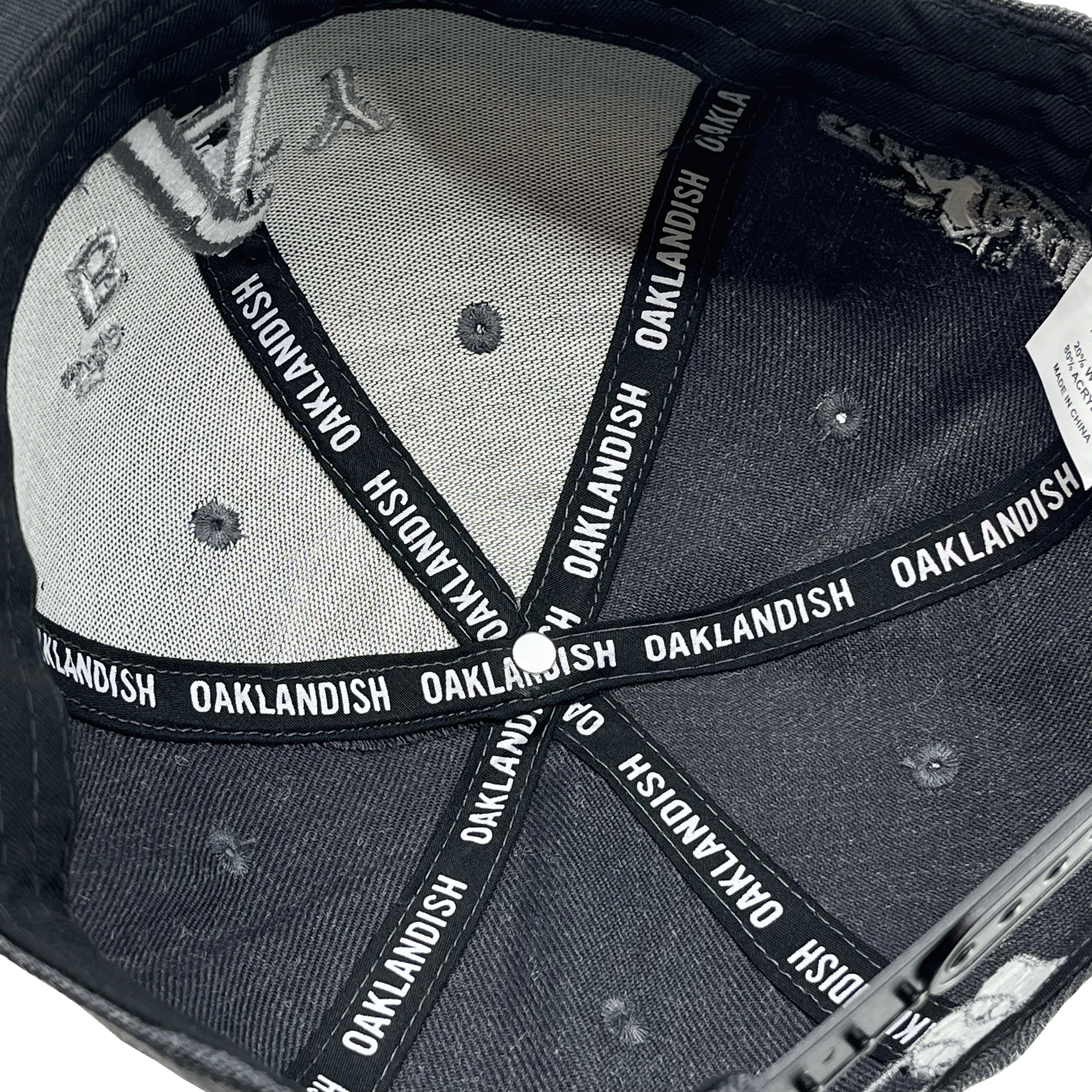 Inside crown view of black taping with Oaklandish wordmark on repeat inside a charcoal cap.