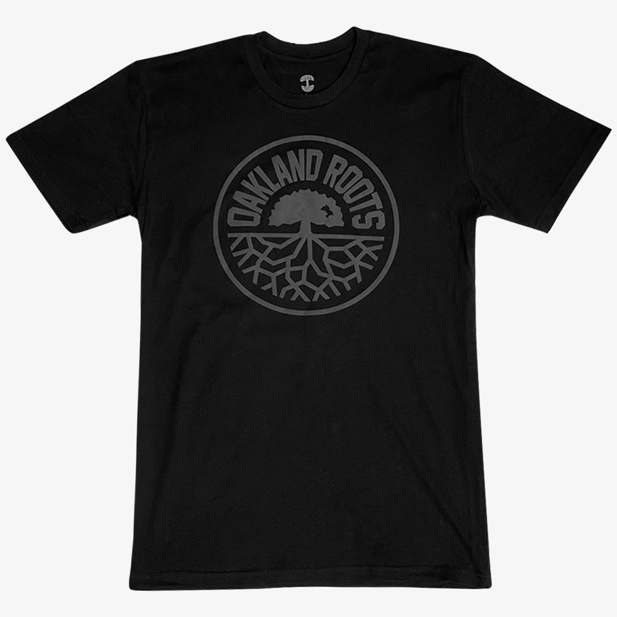 Introducing the Oakland Roots SC Blackout Logo Tee, a black T-shirt proudly featuring a circular emblem at its center. The text "OAKLAND ROOTS" is elegantly arched along the outer edge of the circle, enclosing an intricate illustration of a tree with expansive roots. This design symbolizes both Oaklandish pride and unwavering support for your favorite sports club. The dark-shaded design elements create a subtle yet striking contrast against the black fabric, making it a must-have for any fan.