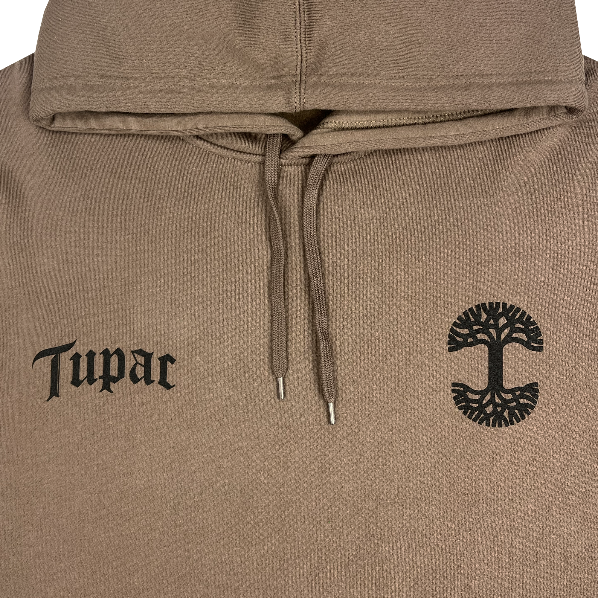 The Bless Hoodie, a collaboration between Oaklandish and Tupac, showcases "Tupac" in black Gothic font on the left chest. On the right side, a black tree design with abstract roots and branches pays homage to Oakland's deep hip-hop heritage. The beige hoodie also features drawstrings hanging down from the center of the hood.