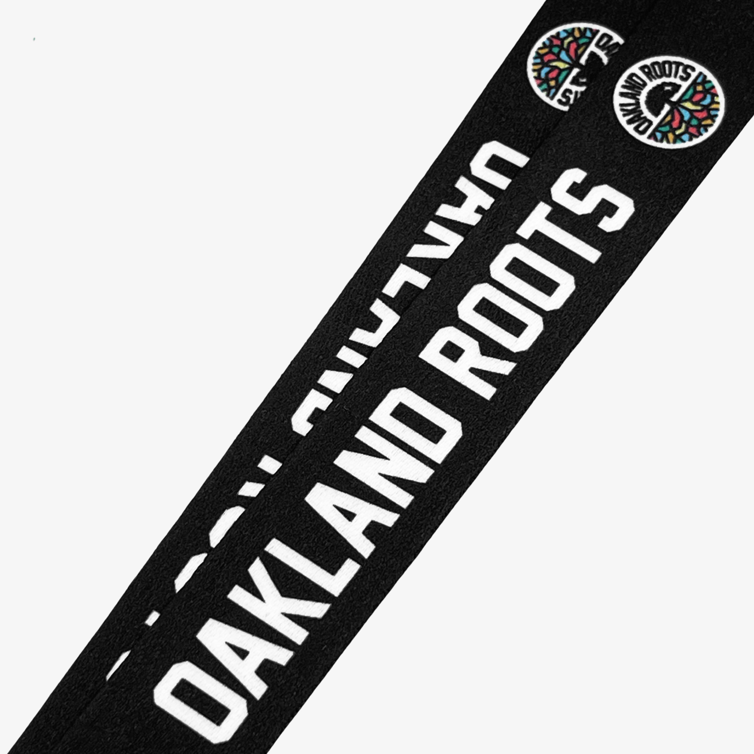 Two black "Oakland Roots SC VIP Lanyards" featuring "OAKLAND ROOTS" written in bold white letters. Each lanyard also showcases the Oakland Roots Sports Club logo, which is a circular design with multicolored roots emanating from the center, embodying the Oaklandish spirit and commitment to social good.