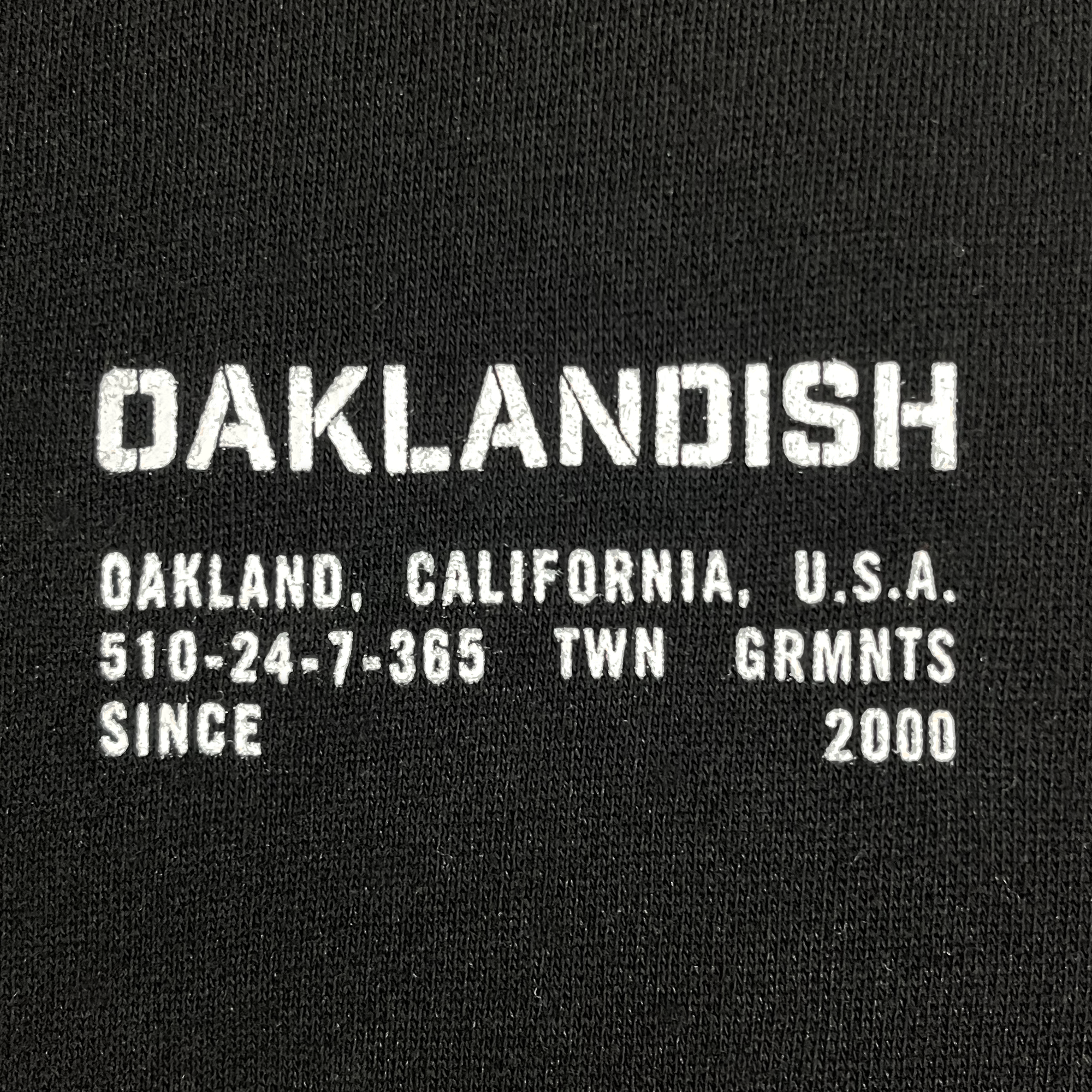 Front  detailed view of Black zip hoodie with Oaklandish wordmark as left chest print.