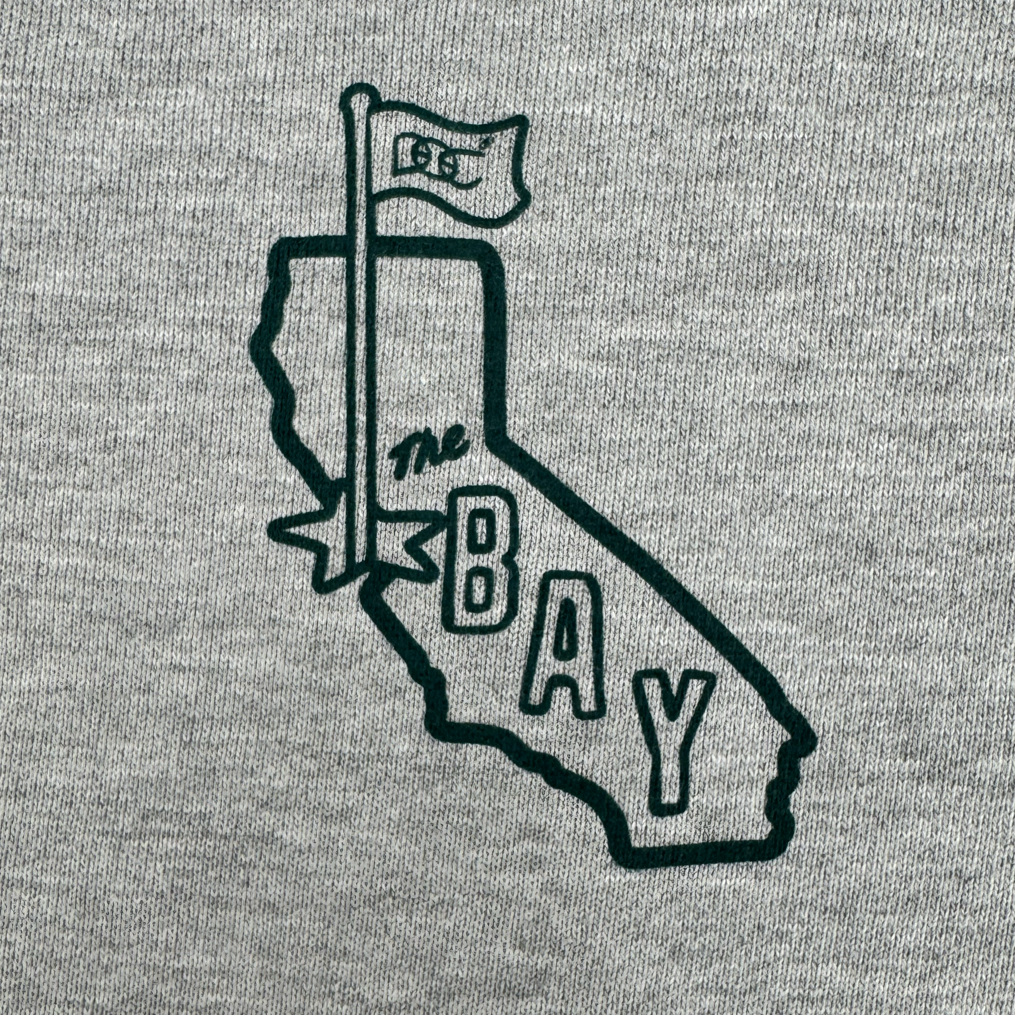 The Bay Flag Crew By DOC by Oaklandish features a hand-drawn black outline of California with a "GSW" flag and "The Bay" text, inspired by the San Francisco Bay Area. Part of The Bay Collection, it's printed on a premium heavyweight crewneck fleece.