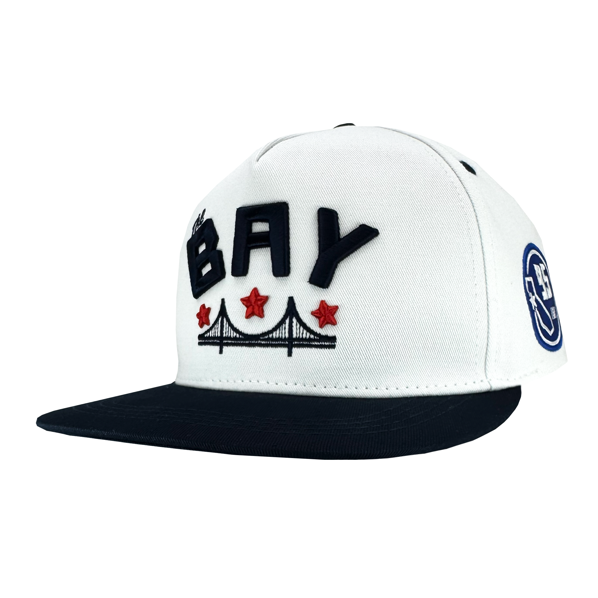 The Bay Bridge Snapback by DOC from Oaklandish is a white and black hat featuring "BAY" in bold black letters. It celebrates Bay Area culture with a bridge illustration and three red stars below. The black brim and circular "9FIFTY" logo on the side complete its design.