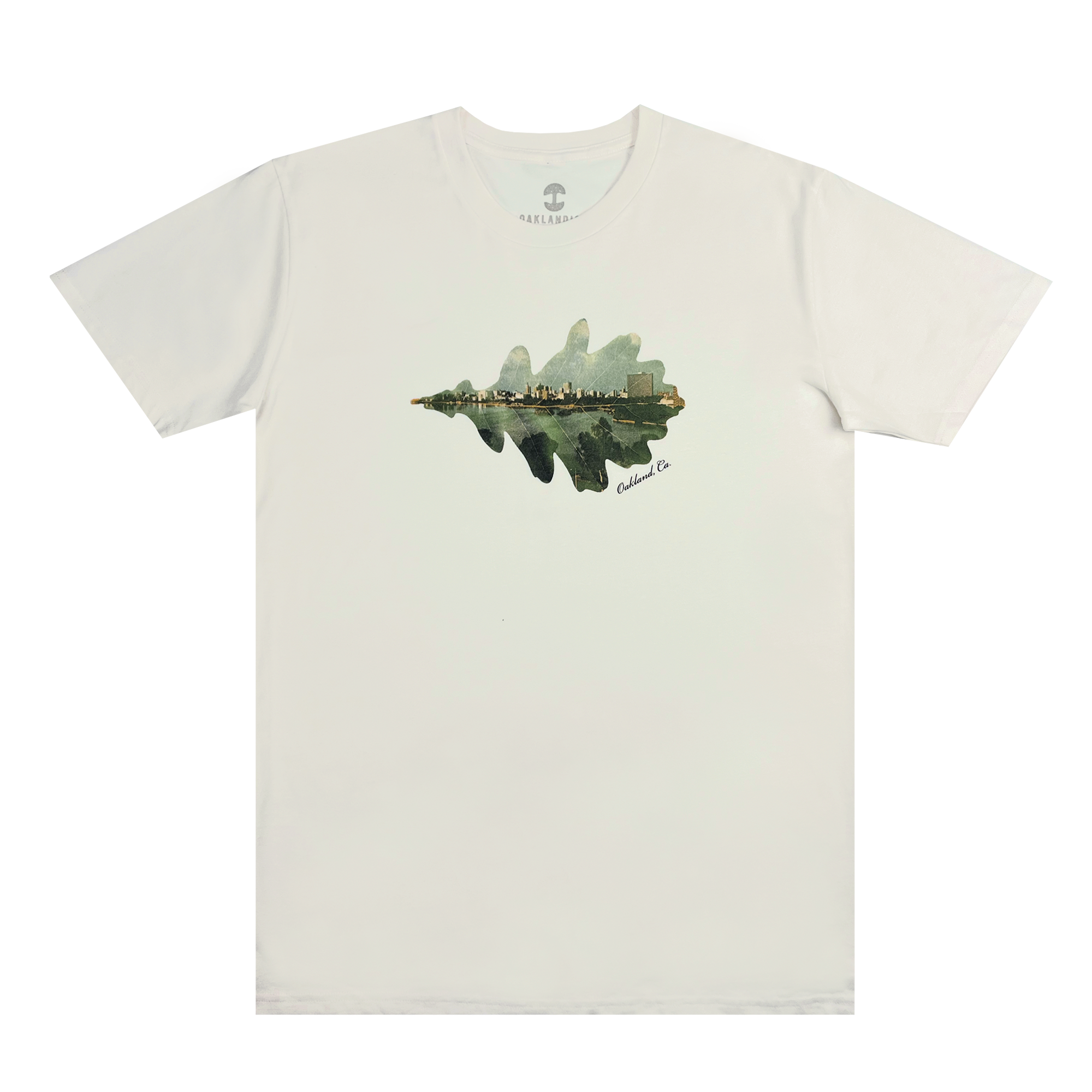 Experience the classic fit of the Double Exposure Tee by Oaklandish—a white T-shirt adorned with a detailed graphic of a cityscape. The design highlights a city skyline reflected in water, creating an intricate mirror image effect. Made from 100% cotton, the artwork is centered on the chest and features subtle green and brown hues, signed "Camden Co" in the bottom right corner.