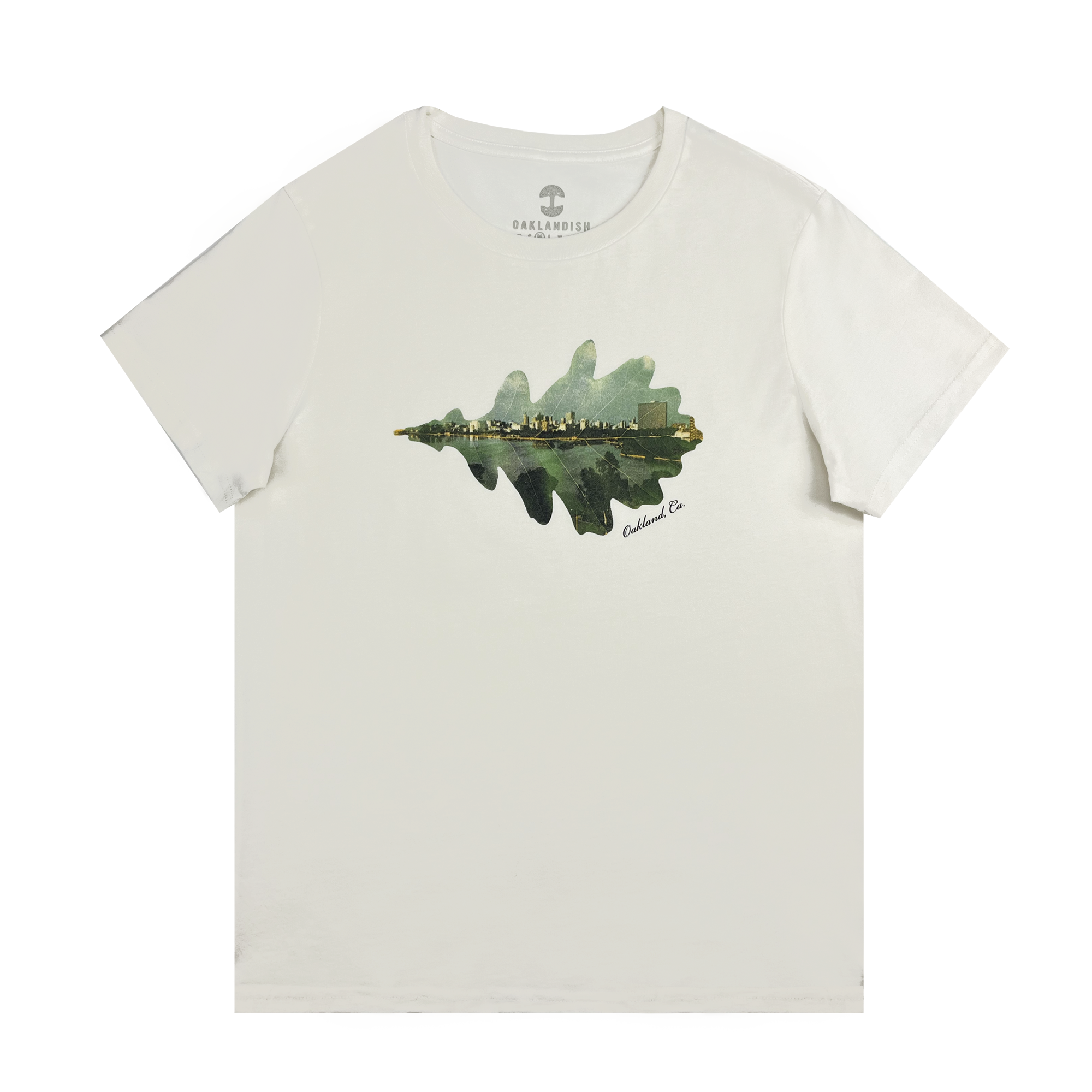 The Women's Double Exposure Tee by Oaklandish features a graphic of a tree with an urban cityscape inside. The city includes buildings and a blue-green landscape, artistically blending natural beauty with urban life. The brand label "Oaklandish" is visible at the neck.