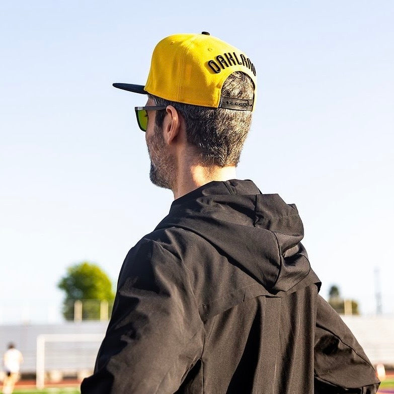 Guy at an angle wearing hat so that you can see back embroidery.