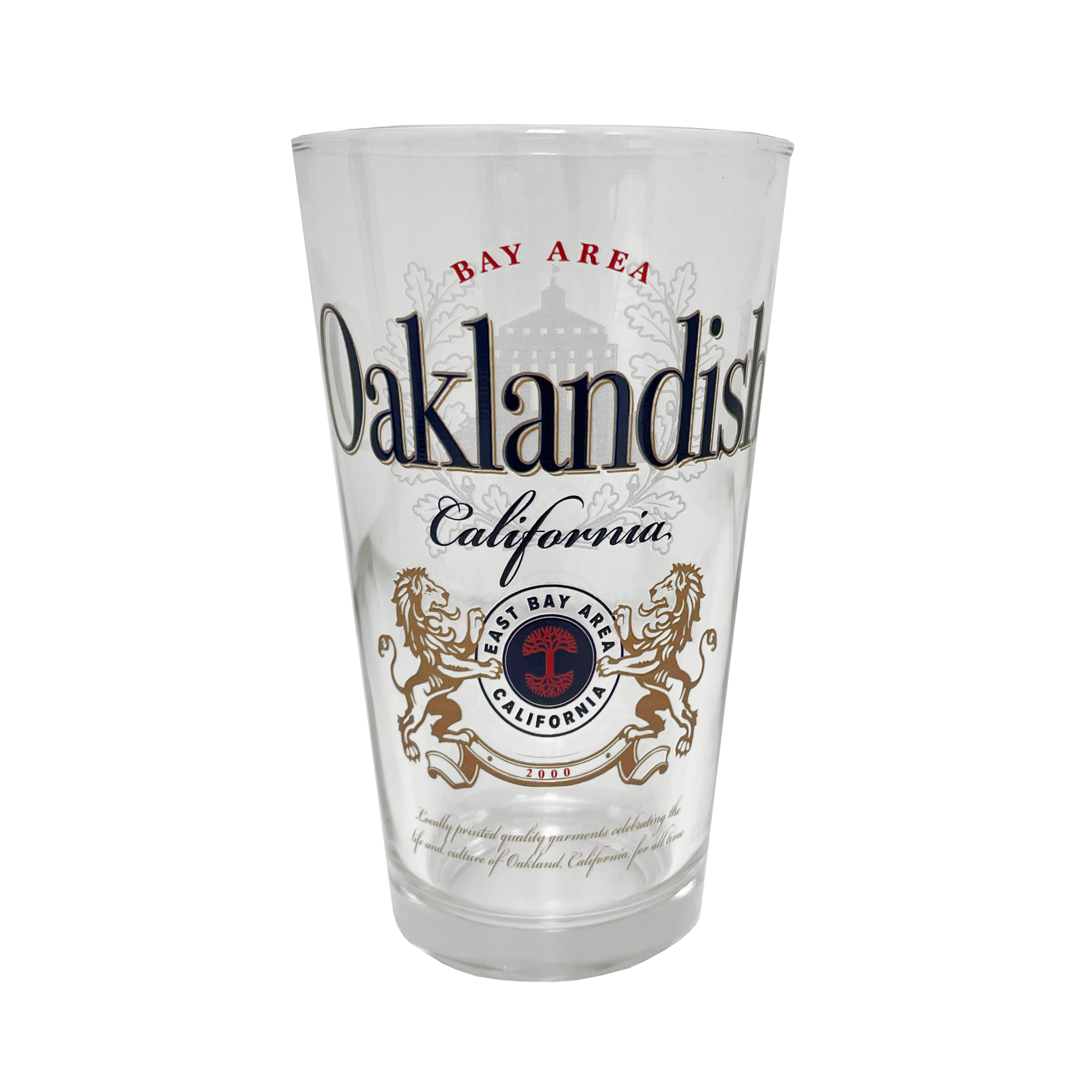 The Oaklandish Lager Pint Glass boasts a bold, ornate design with "Bay Area Oaklandish California" text. This 16 oz pint glass features a crest adorned with two golden lions facing each other, encircling a tree with the text “East Bay Area California.” Intricate design elements flawlessly blend text and graphics.