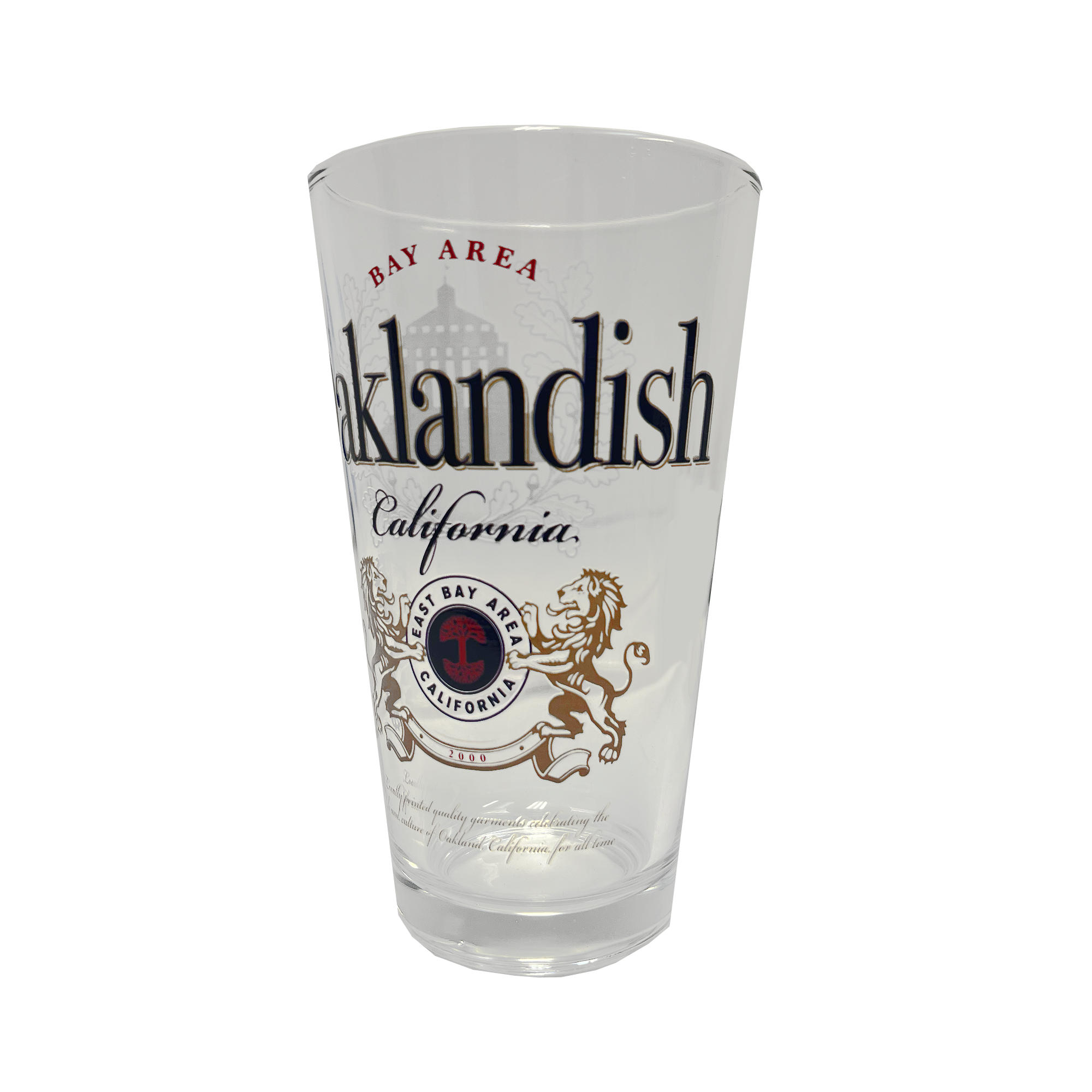 The **Lager Pint Glass** by **Oaklandish** is a stylish 16 oz pint glass featuring "Oaklandish" and "California" in bold black text. Above "Oaklandish," "Bay Area" is written in red, while below, a circular emblem displays "Bay Area California" flanked by two lions. The background of this practical drinkware is white, combining local pride with everyday functionality.