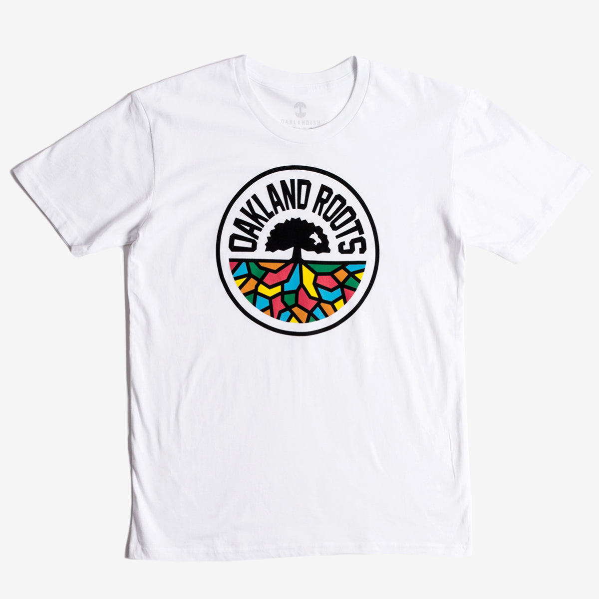 The Oakland Roots SC Classic Tee from Oakland Roots SC showcases a striking circular logo in the center. At its heart is a black tree with sprawling roots, accompanied by the text "Oakland Roots" elegantly arched above it. The roots branch out into vibrant sections of red, blue, green, and yellow, forming a stained-glass effect that symbolizes the club's commitment to social good.