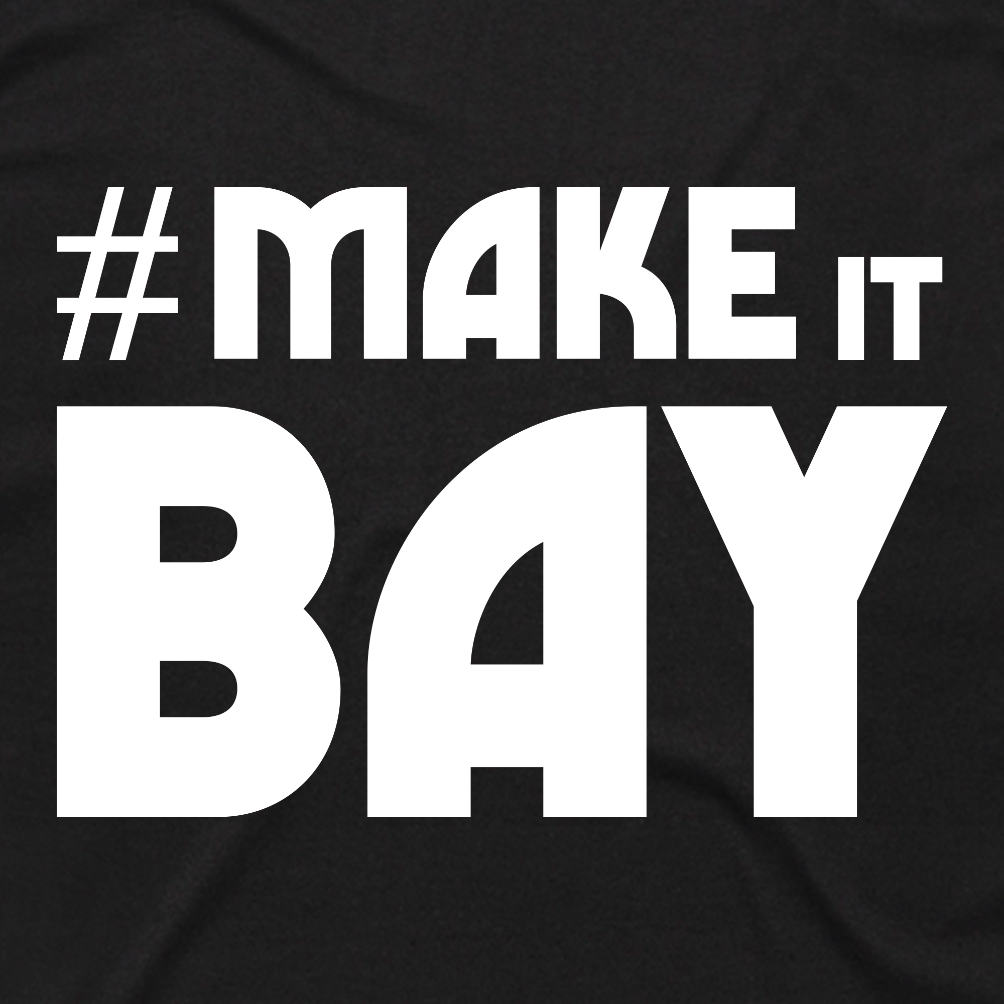 The Make It Bay Tee by Oaklandish features bold white text—“MAKE IT” in all caps above a larger “BAY”—on a black background. This striking graphic design celebrates Bay Area creatives in an exclusive Oaklandish collaboration.