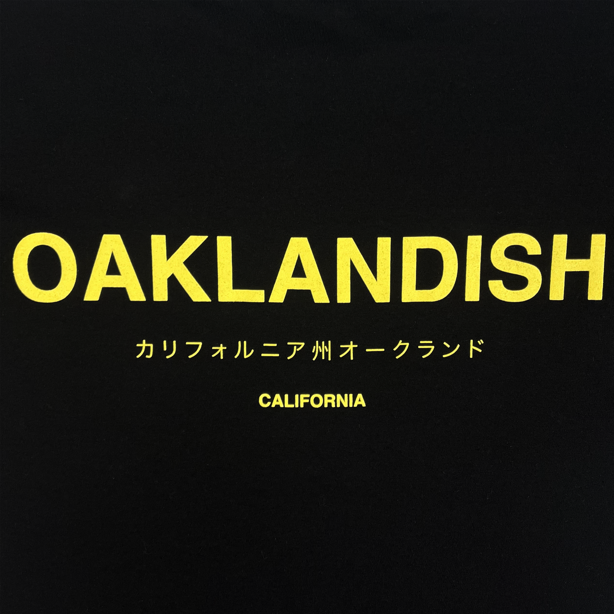 Detailed view of black cotton t-shirt with Oaklandish California wordmark in English and Japanese.