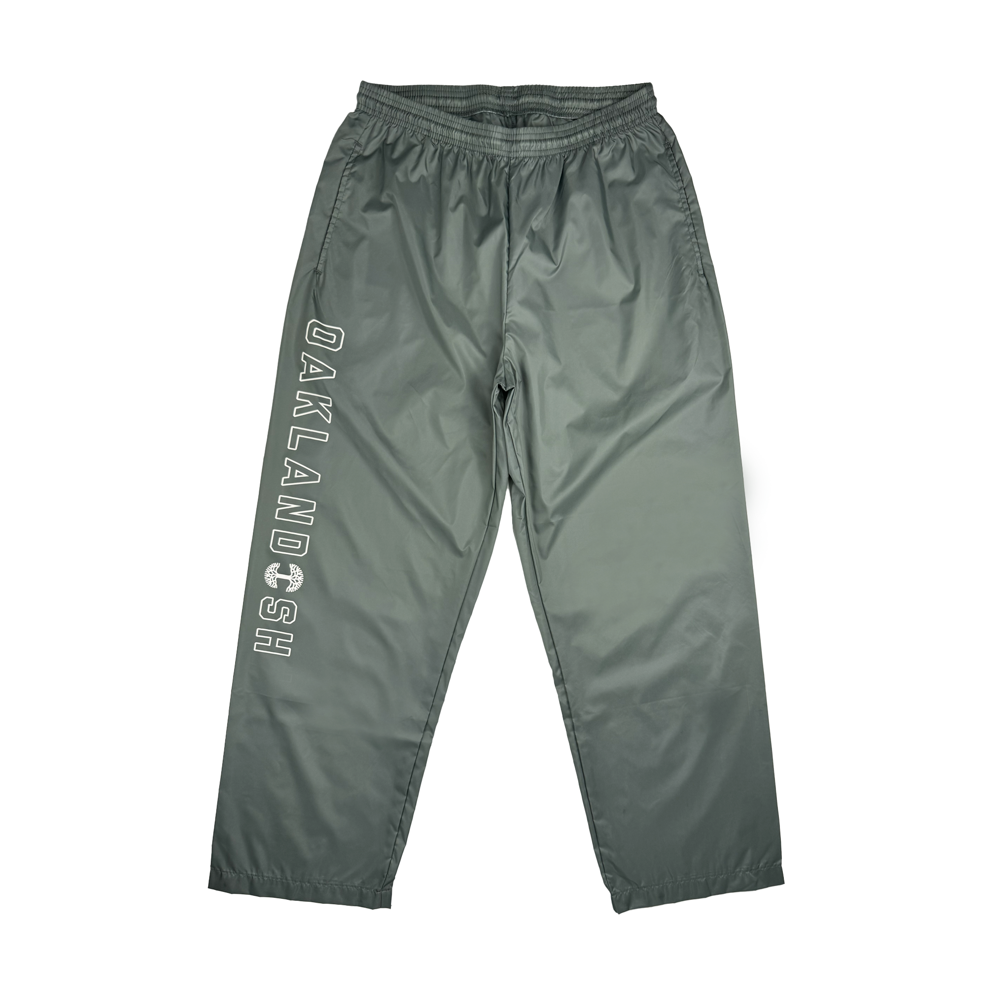 The Bandit Nylon Pant by Oaklandish is a pair of gray nylon taffeta track pants with "OAKLANDISH" boldly printed in white letters down the left leg. These pants feature an adjustable waistband and a straight-leg design, made from smooth, shiny fabric for a casual and sporty look.