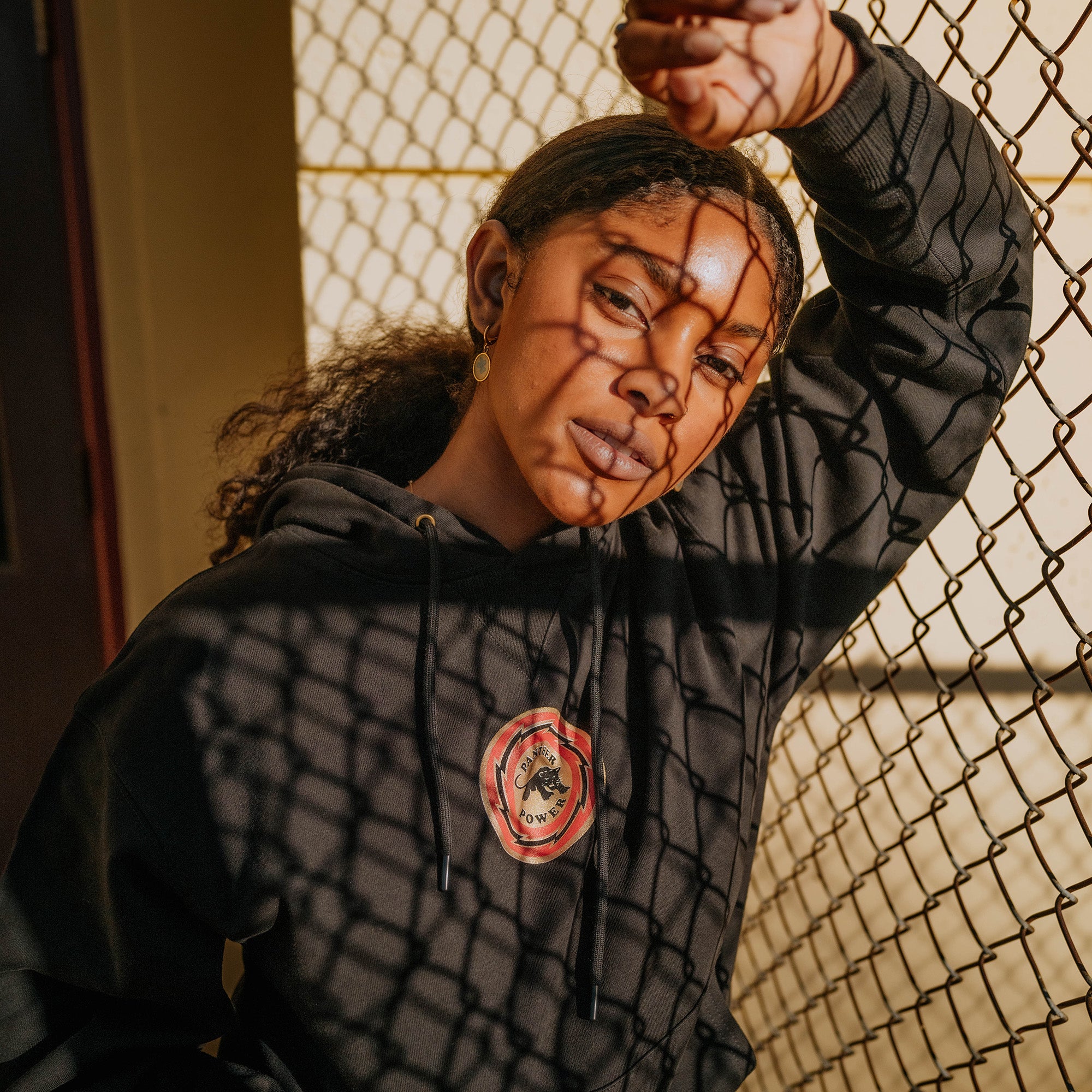 Front view of female model wearing black limited edition collector's hoodie with small Panther Power circle graphic on the chest.