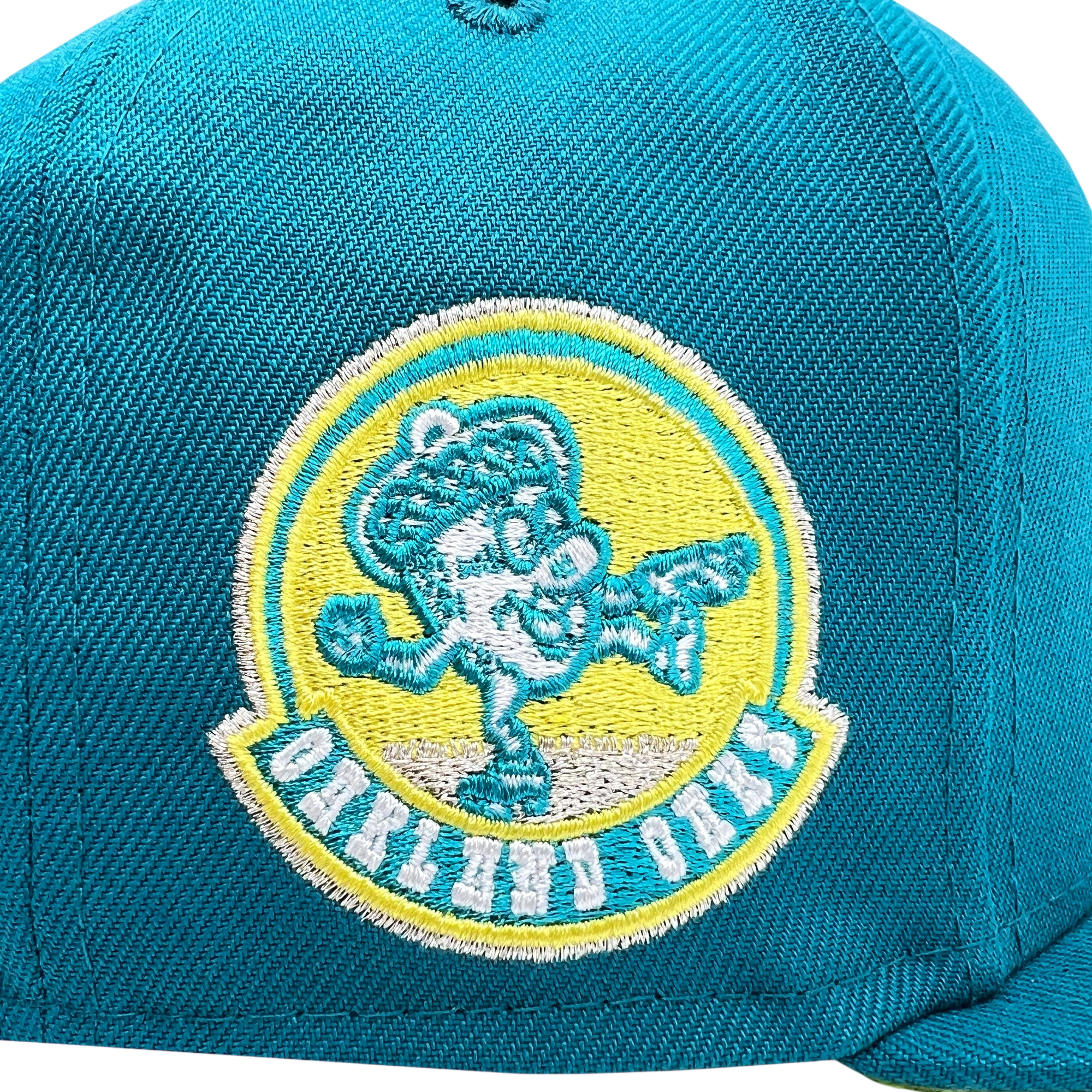 The New Era Oakland Oaks 59FIFTY Fitted Cap by Other showcases a vibrant teal design with an eye-catching, teal embroidered patch of a cheerful cartoon baseball character wearing an oversized hat and pointing, set within a yellow and green circle. “OAKLAND OAKS” is stitched in crisp white at the base of the patch, giving this fitted cap a playful yet iconic appeal.