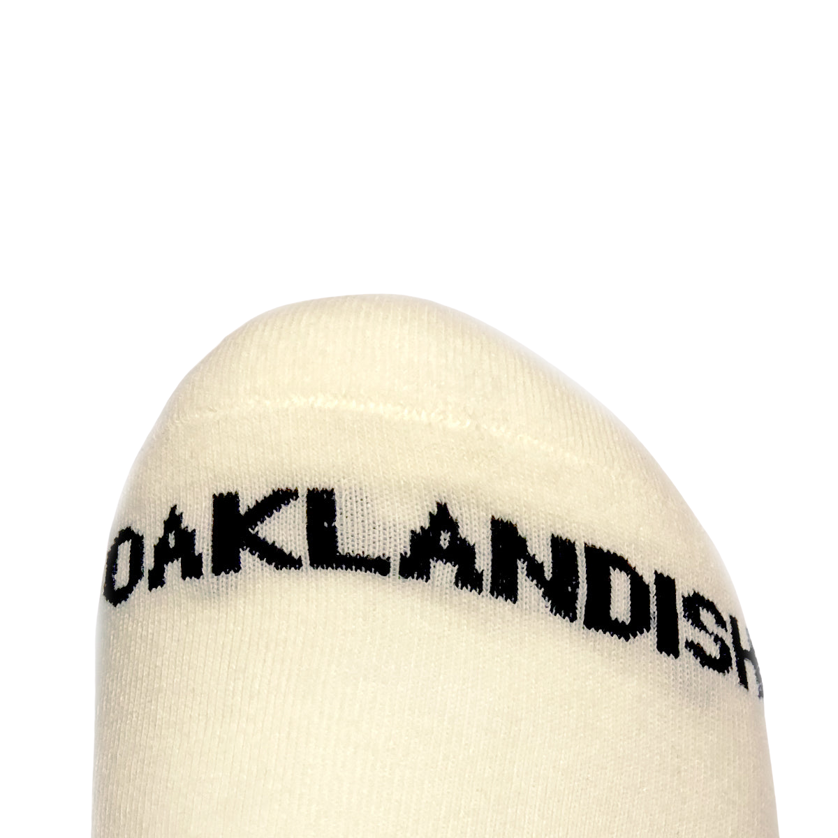 A close-up of the toe area of Embroidered Logo Socks from Oaklandish against a plain background. The word "OAKLANDISH" is printed in bold, black letters across the top, showcasing an embroidered logo. The stitching and fabric texture are clearly visible.