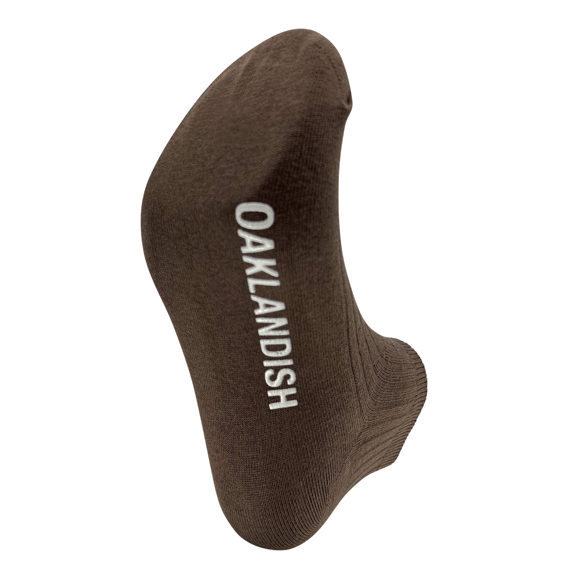 The Oaklandish Grip Low Crew Sock is a single brown cotton low crew sock with the brand name "OAKLANDISH" in white capital letters running vertically. Photographed on a white background, the image highlights the heel and toe portions of the sock, emphasizing its fabric texture and simple design.