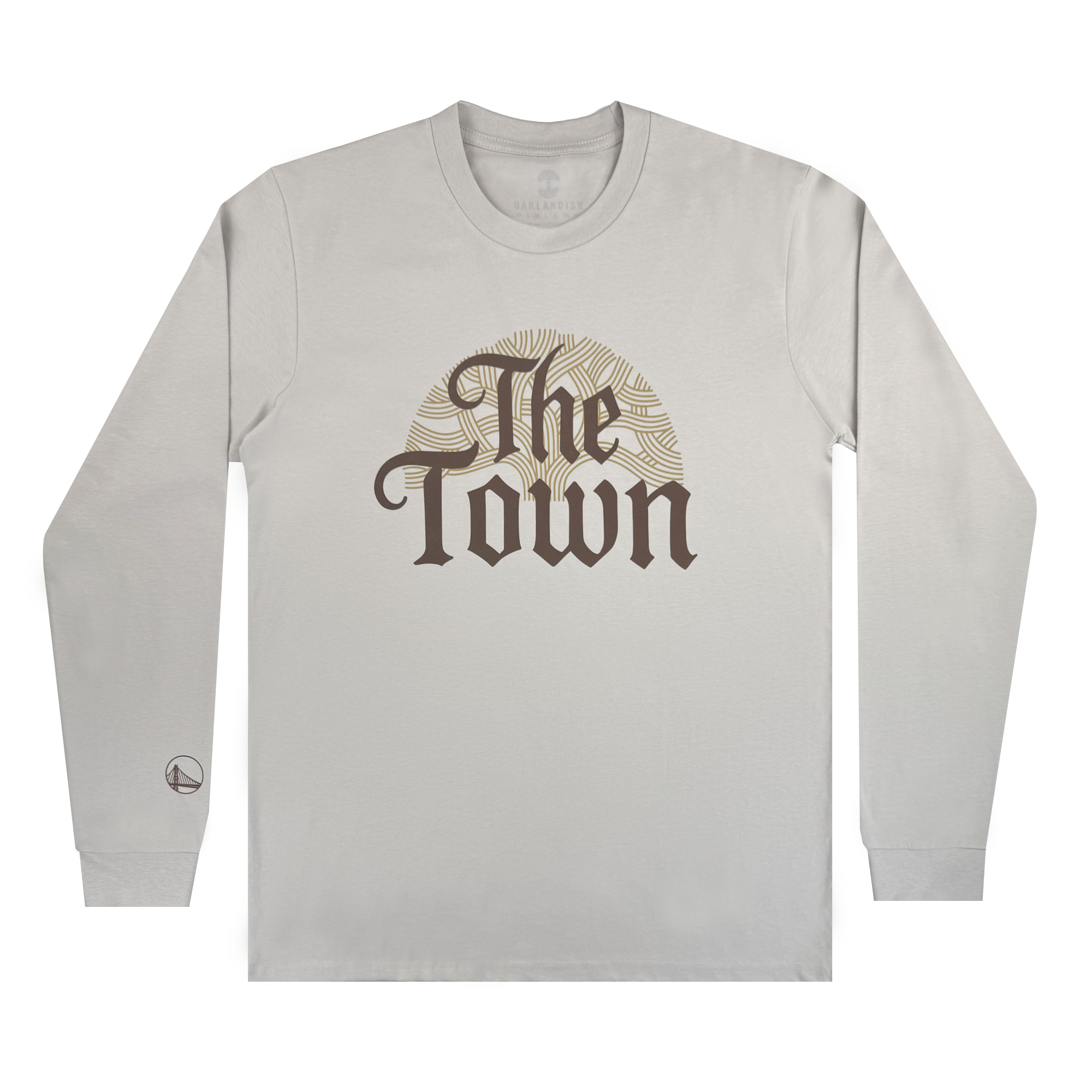 The GSW Pirate Black-Letter LS Tee is a light gray long-sleeve shirt with bold, dark “The Town” text and a subtle gold circle pattern—a nod to Golden State Warriors pride. A small circular logo accents the left wrist.