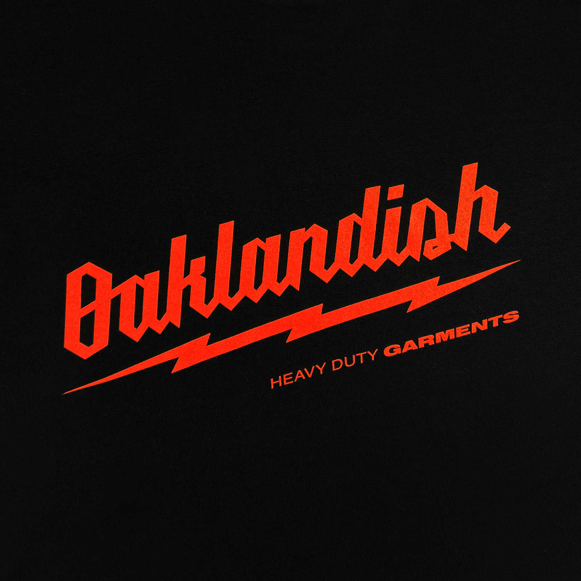 The Power Tools Tee by Oaklandish is a black t-shirt with the word "Oaklandish" showcased in bold, bright red, stylized text accompanied by a lightning bolt underline. Below it, you'll find the words "HEAVY DUTY GARMENTS" in smaller red text. This classic fit t-shirt is crafted from 100% cotton.