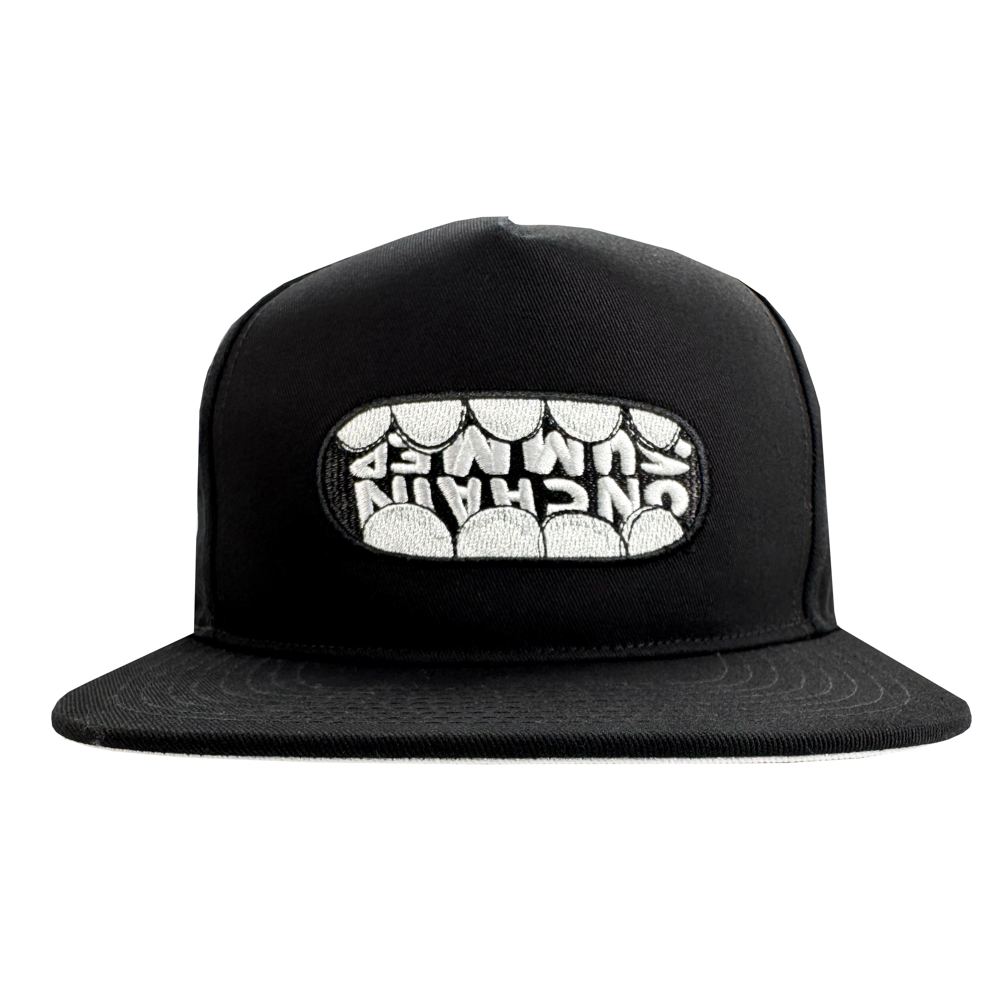 The OG Snapback Hat by Supported Brands is a black adjustable snapback featuring a front embroidered patch where stylized white teeth spell “UNCHAIN” across the upper row. Photo shows the hat on a plain white background.
