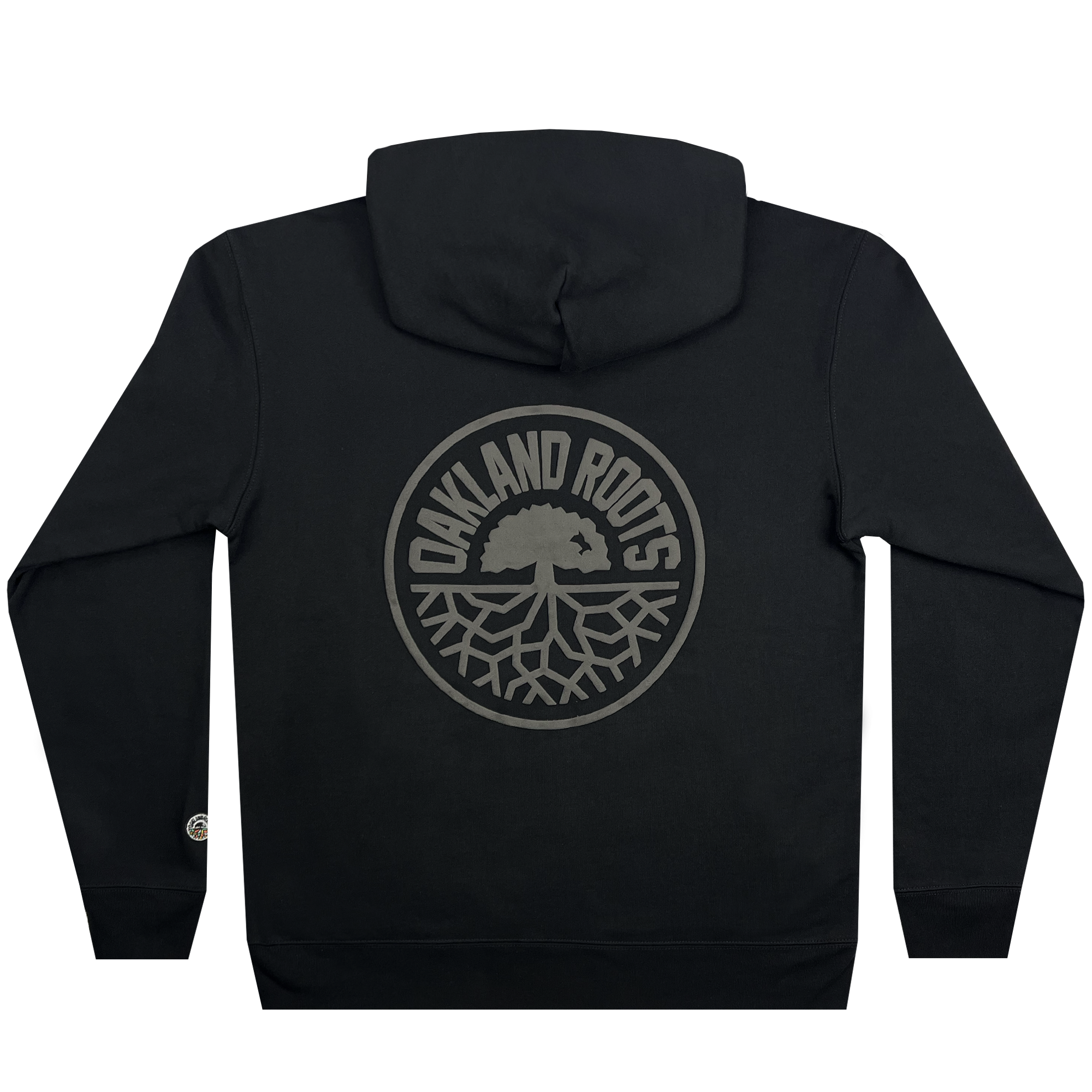 The Oakland Roots SC Ascetic Hoodie by Oakland Roots SC is a black hooded sweatshirt crafted from organic cotton. It features the "OAKLAND ROOTS" text encircling an image of a tree with exposed roots in a gray circular emblem on the back. The design is centered and occupies a significant portion of the back, embodying an authentic Oaklandish style.