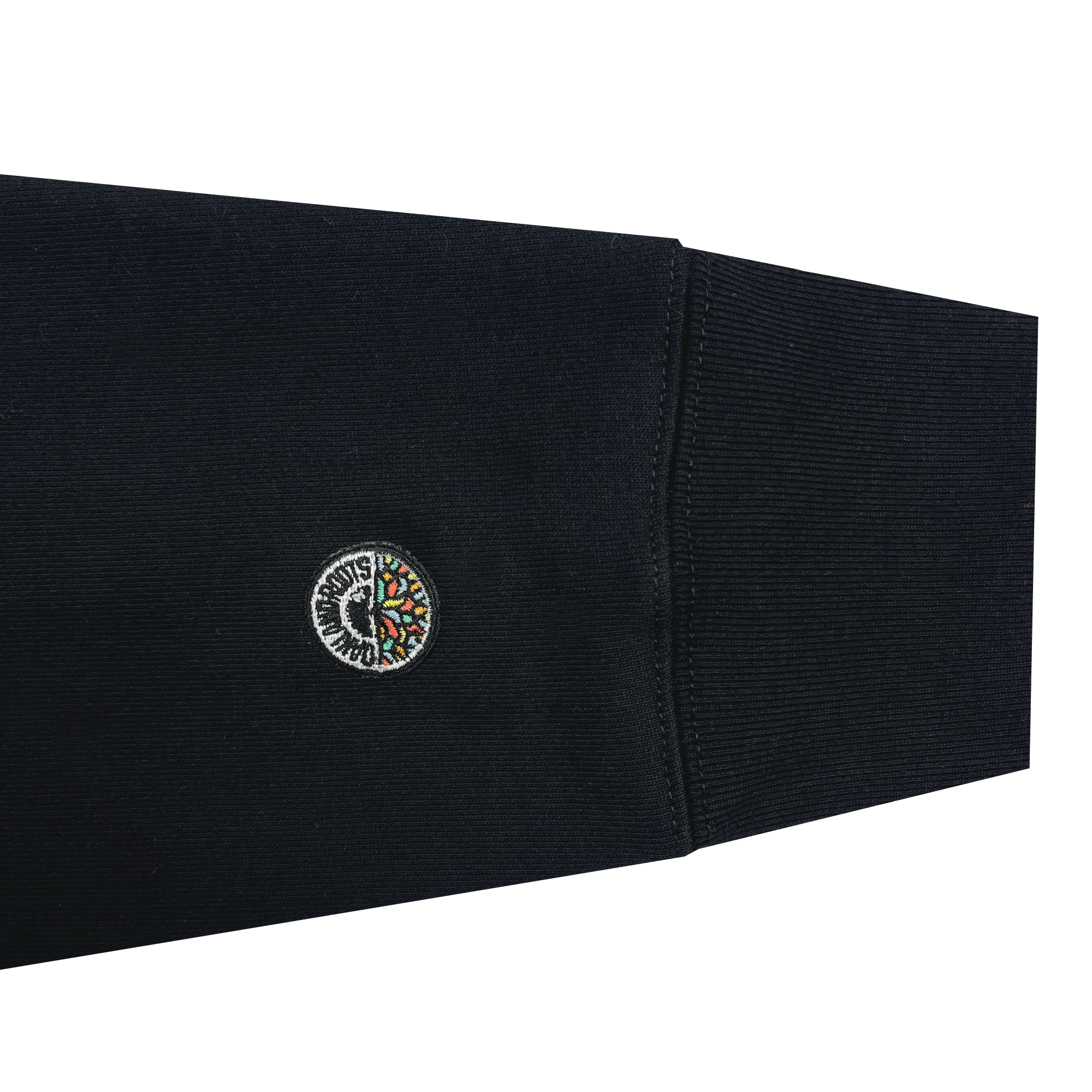 The image shows the sleeve of the dark-colored, long-sleeve Oakland Roots SC Ascetic Hoodie, made from organic cotton. It features a small, circular embroidered patch near the wrist with an intricate design reminiscent of Oaklandish. The fabric of the sleeve appears ribbed at the cuff.