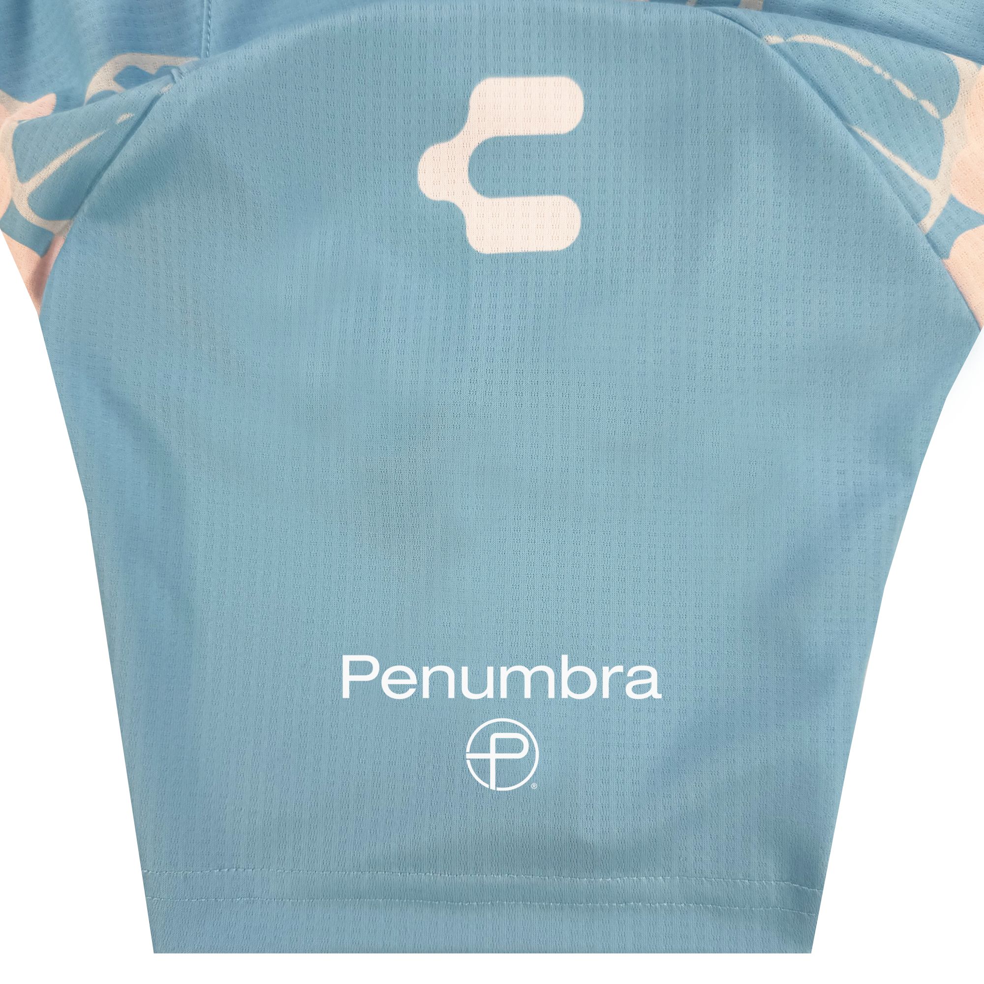 A close-up of light blue Oakland Soul fabric from the Unisex Butterfly Effect Kit shows "Penumbra" in white text above a circular logo, with a curved white abstract symbol above. The textured material appears to be part of a sports jersey.