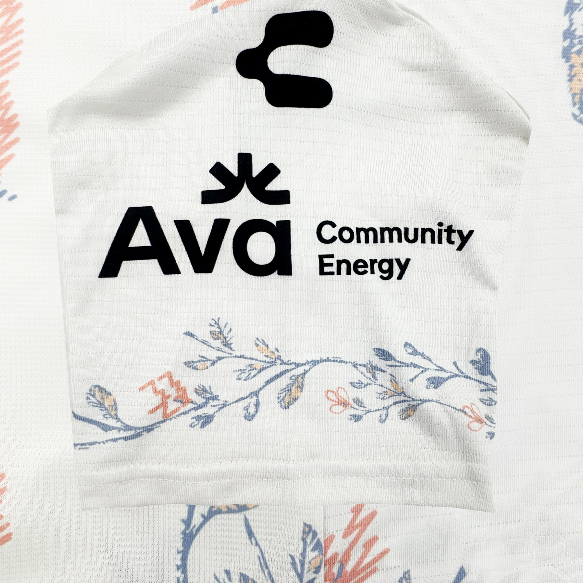 A white Oakland Soul custom 2026 SC Form jersey displays "Ava Community Energy" in bold black text with a logo above. Delicate blue and peach floral patterns accent the bottom and background, offering a soft, stylish look.