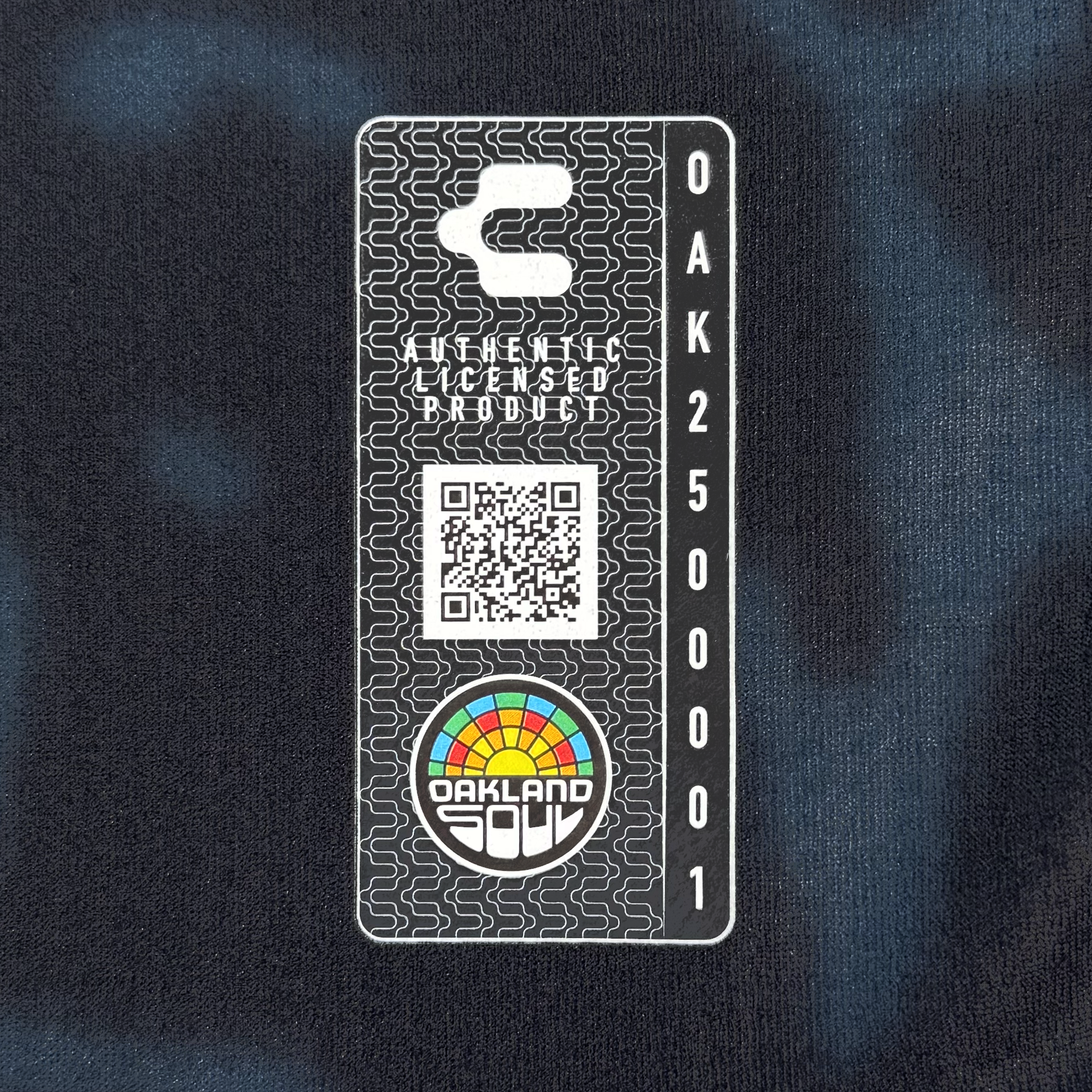 The Unisex Soul Bloom Kit by Oakland Soul features a rectangular patch with a barcode, QR code, rainbow “OAKLAND SOUL” logo, “OFFICIALLY LICENSED PRODUCT” above the QR code, "OAK2500001" vertically on the right, and a dark Oakland floral tie-dye background.