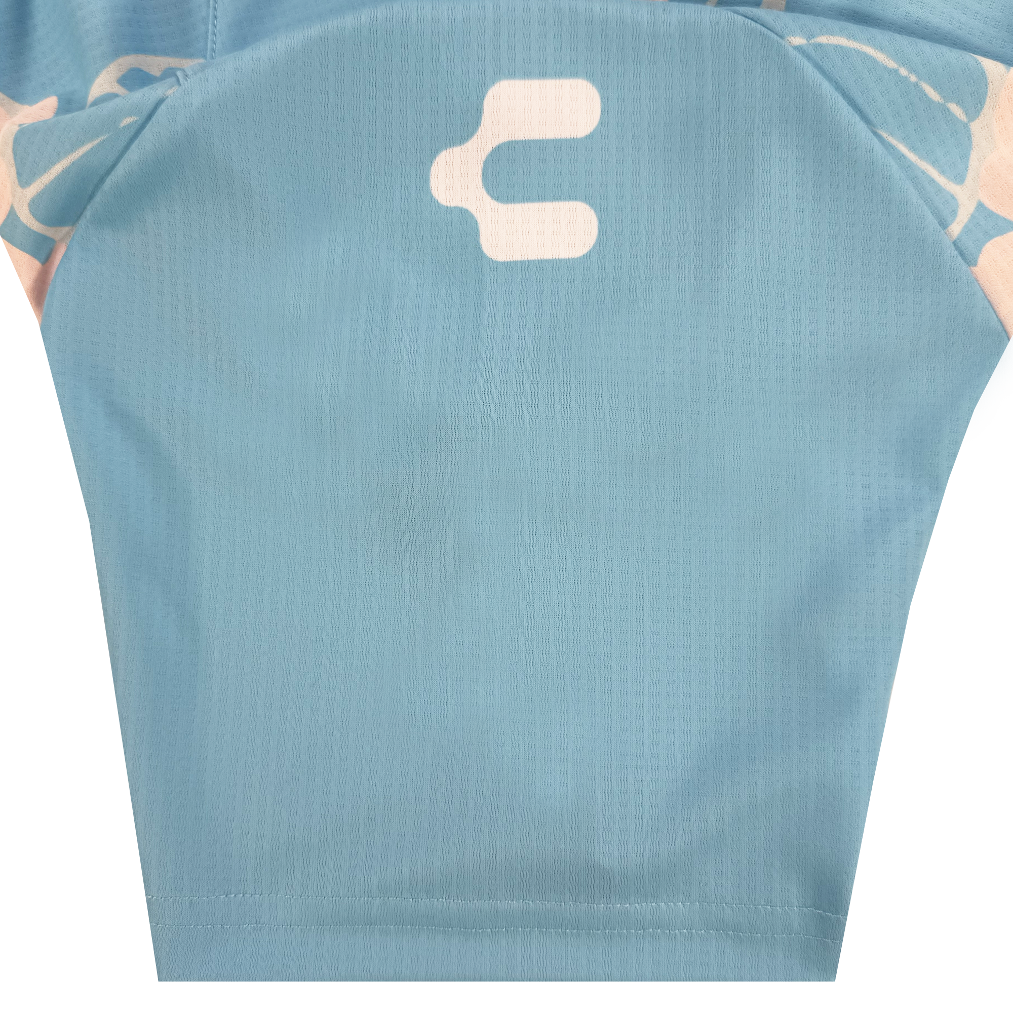 A close-up of the Unisex Butterfly Effect Kit by Oakland Soul shows light blue textured fabric with a white abstract symbol, plus hints of peach and blue pattern inspired by Oakland Roots—suggesting stylish sportswear or cycling jersey design.