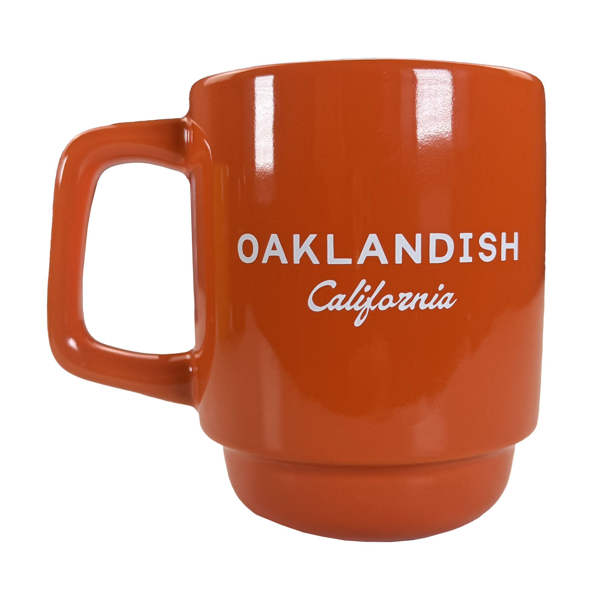 The Oaklandish Logo Stack Mug is an orange ceramic drinkware cup with a squared handle and "OAKLANDISH California" printed in white, shown on a white background. The design is minimal, with no extra decorations or graphics.