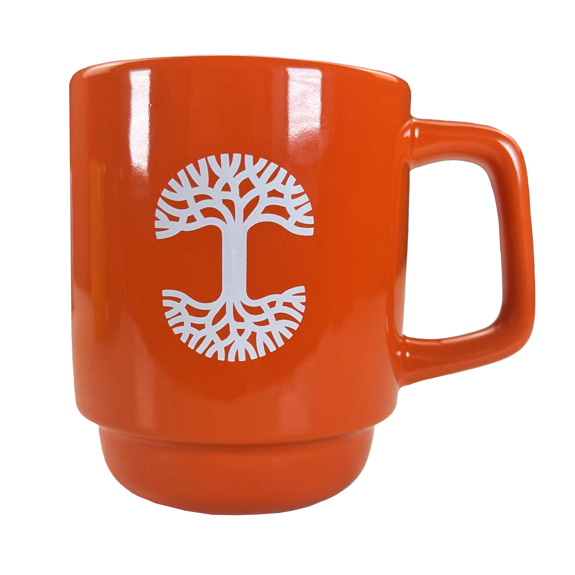 The Oaklandish Logo Stack Mug is an orange ceramic coffee cup with a large handle, featuring a white stylized tree with spreading roots and branches centered on the front. The background is plain white.