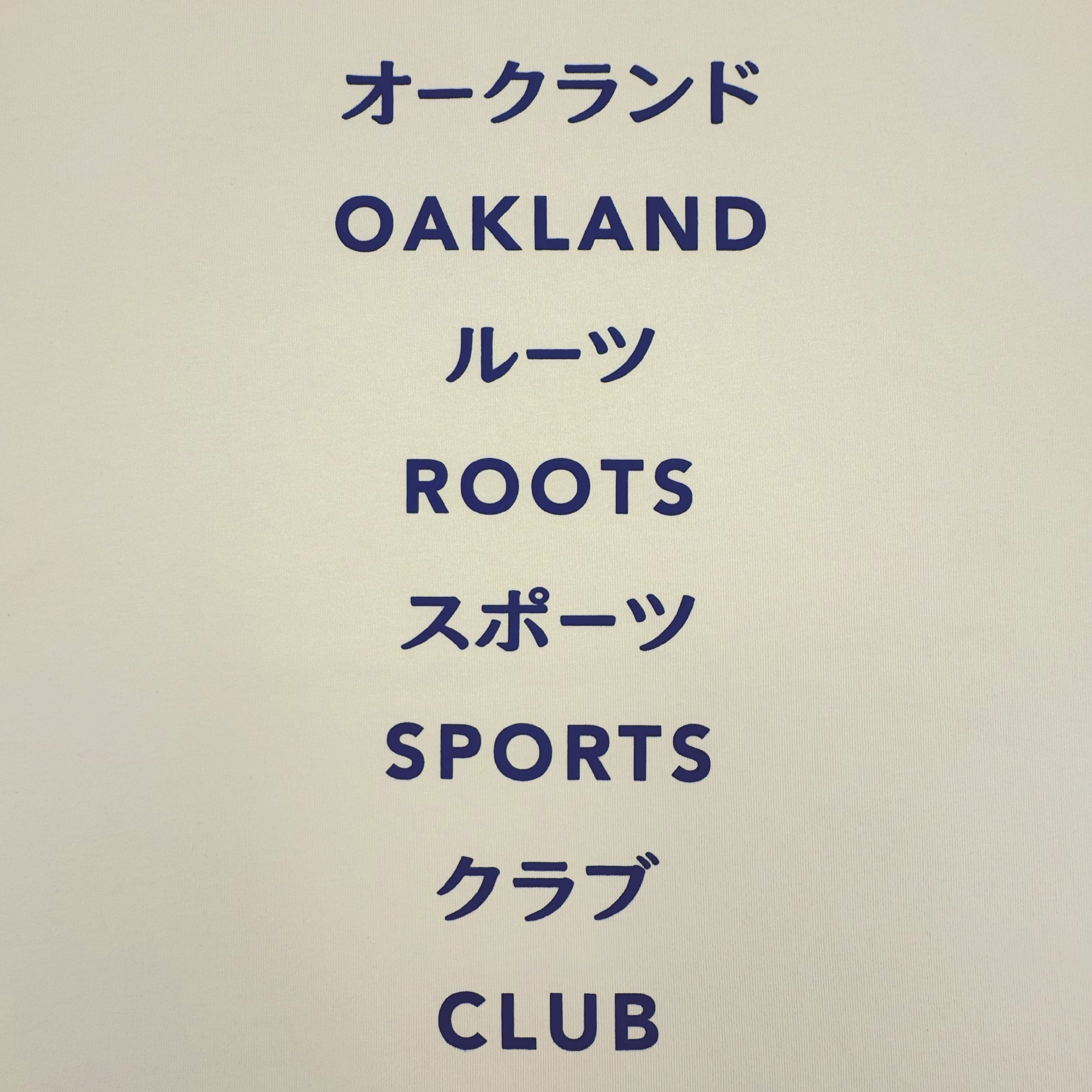 Text on a plain background reads: オークランド (Oakland), ルーツ (Roots), スポーツ (Sports), クラブ (Club), with each English word below its Japanese equivalent—perfect for fans of the Oakland Roots SC Story Telling Tee.