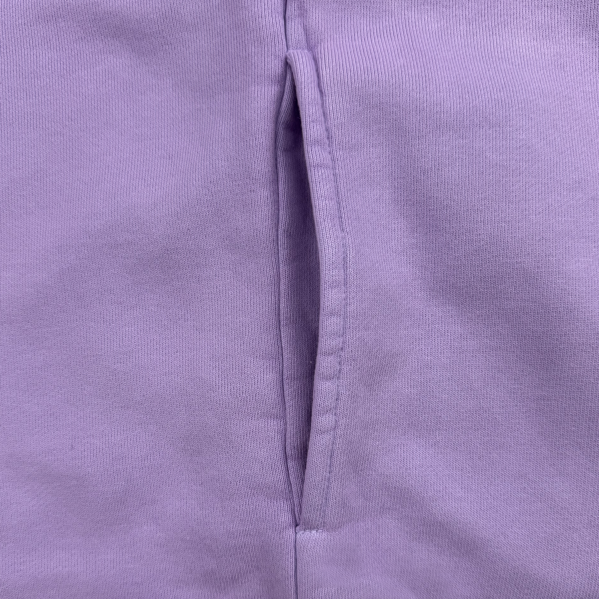 Close-up of the Golden State Valkyries Primary Heavy Crewneck by GSV. The lavender organic cotton fabric features a vertical pocket with neat stitching. This heavyweight, preshrunk material is soft with a subtle, textured weave and highlights the garment's quality construction.