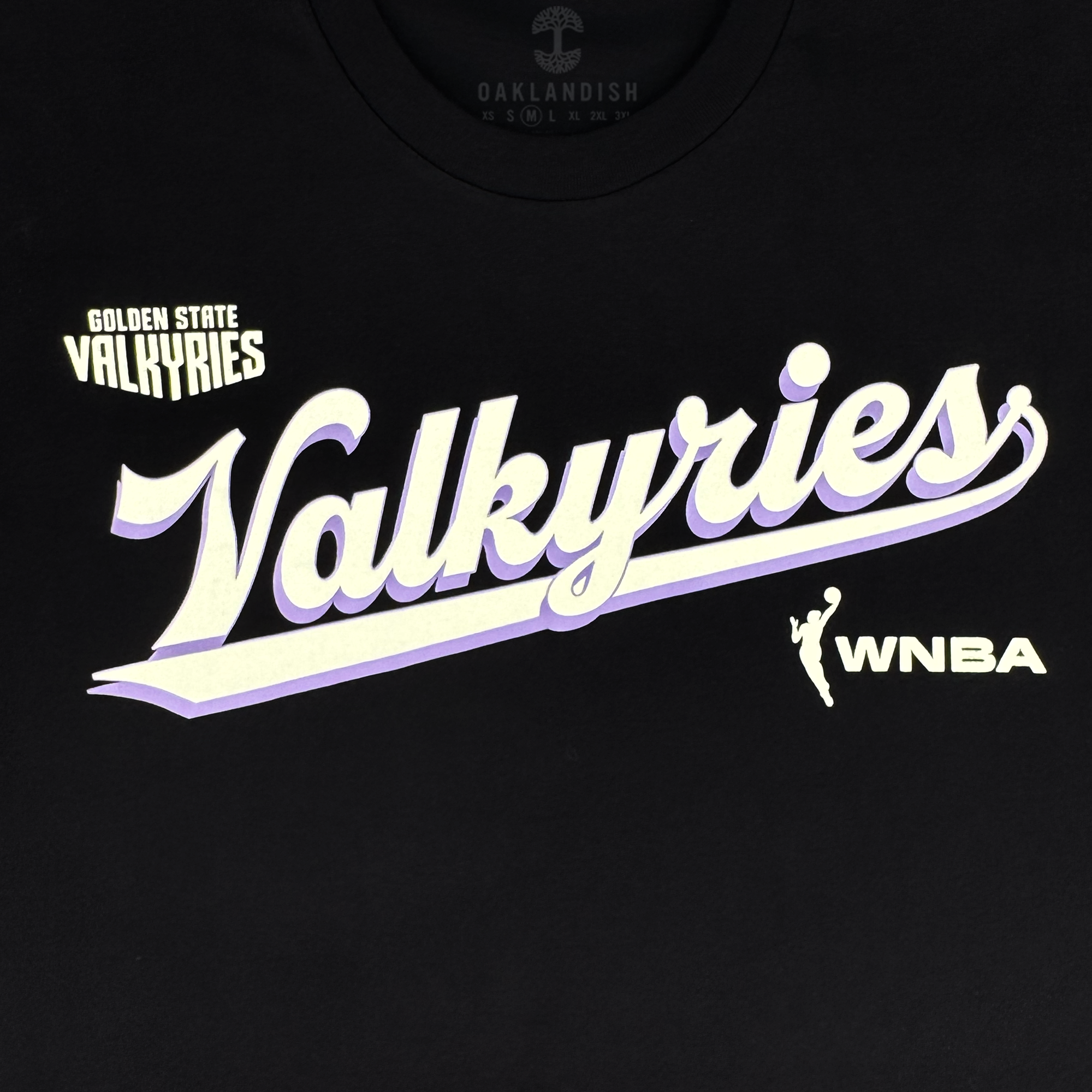 The GSV Golden State Valkyries Retro Script Tee is a black heavy organic cotton shirt with bold "Golden State Valkyries" text, a large white script "Valkyries" with purple underline, WNBA logo on the right, and subtle "Oaklandish" at the collar.