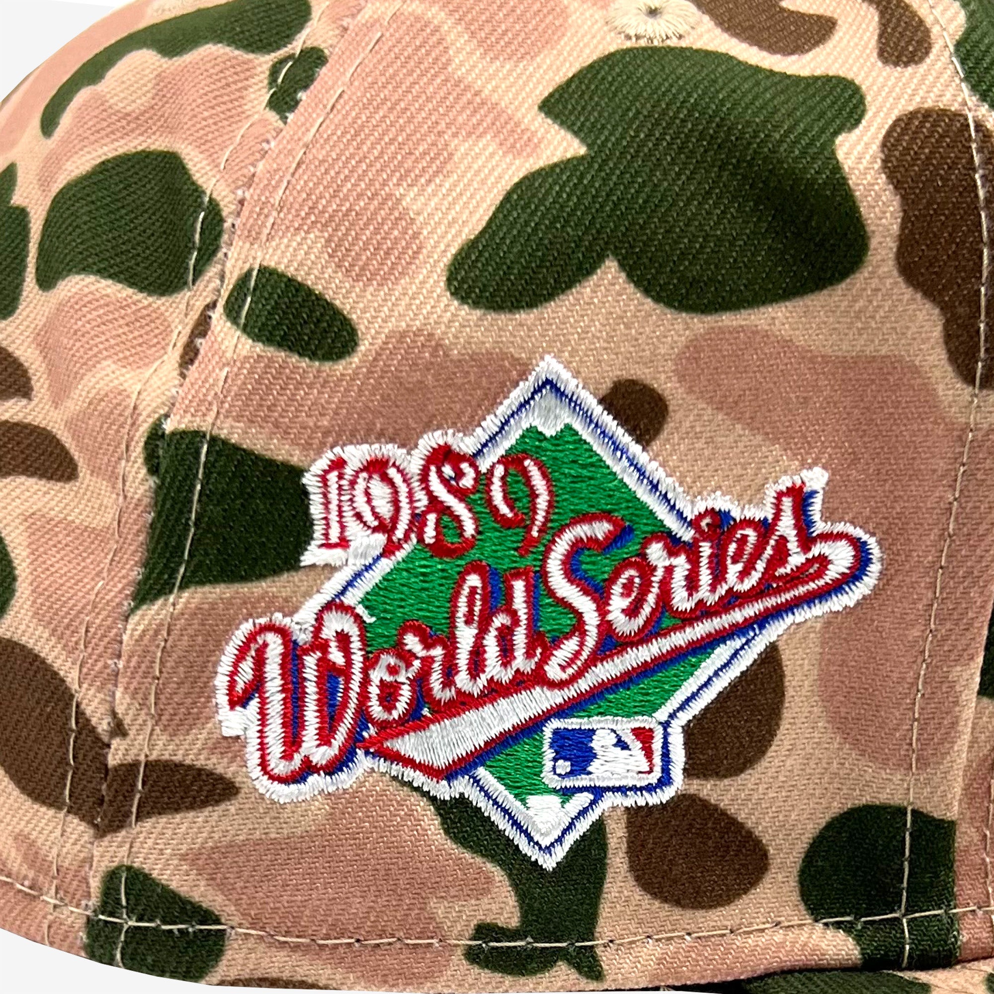 A close-up of the New Era Oakland A's 59FIFTY fitted cap by Retail Vendors, showcasing a stitched emblem for the 1989 World Series. The design features "1989 World Series" in red script on a green diamond background, with the Major League Baseball logo at the bottom. The Duck Camo fabric pattern includes shades of green and brown.