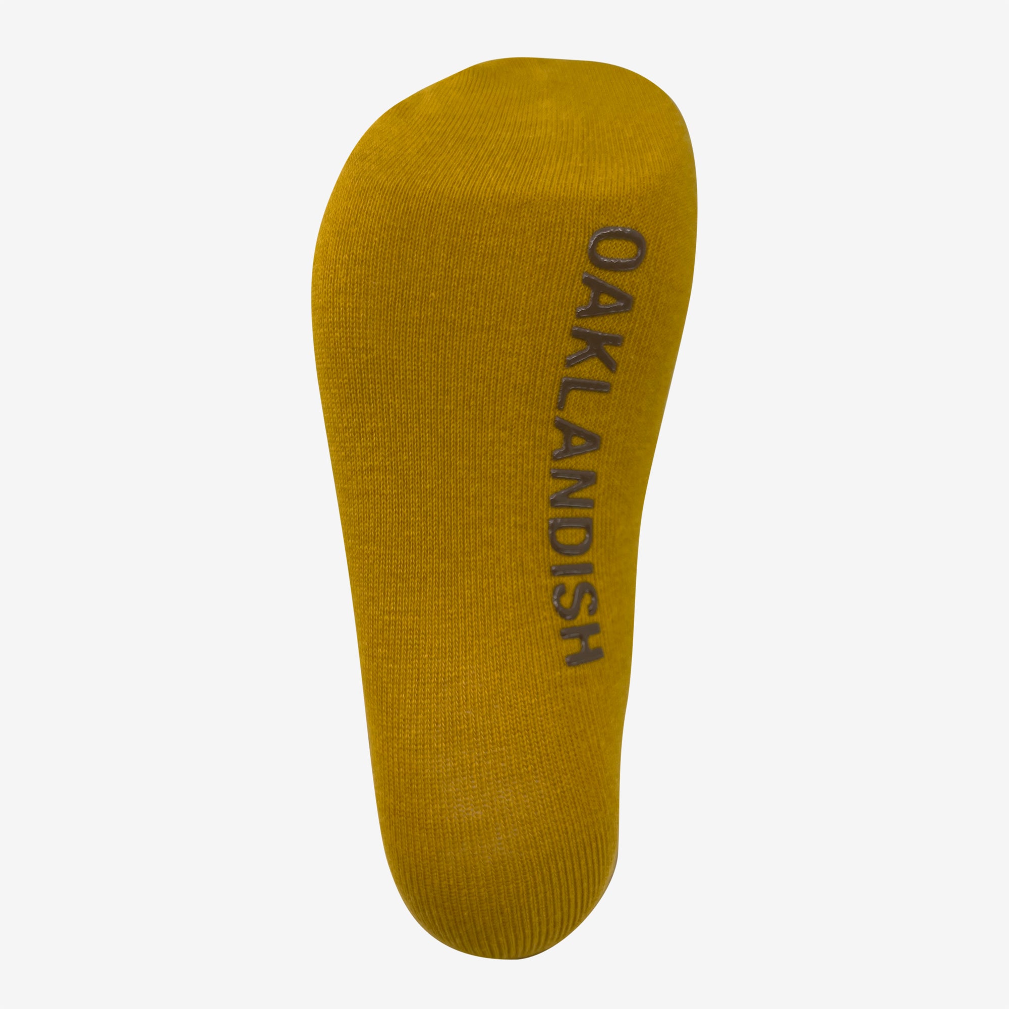 A single yellow sock is shown with the word "OAKLANDISH" printed in black along the length of the sole. The Oaklandish Grip Crew Sock, made from a blend of cotton, polyester, and spandex, is displayed against a white background and appears new and unworn.