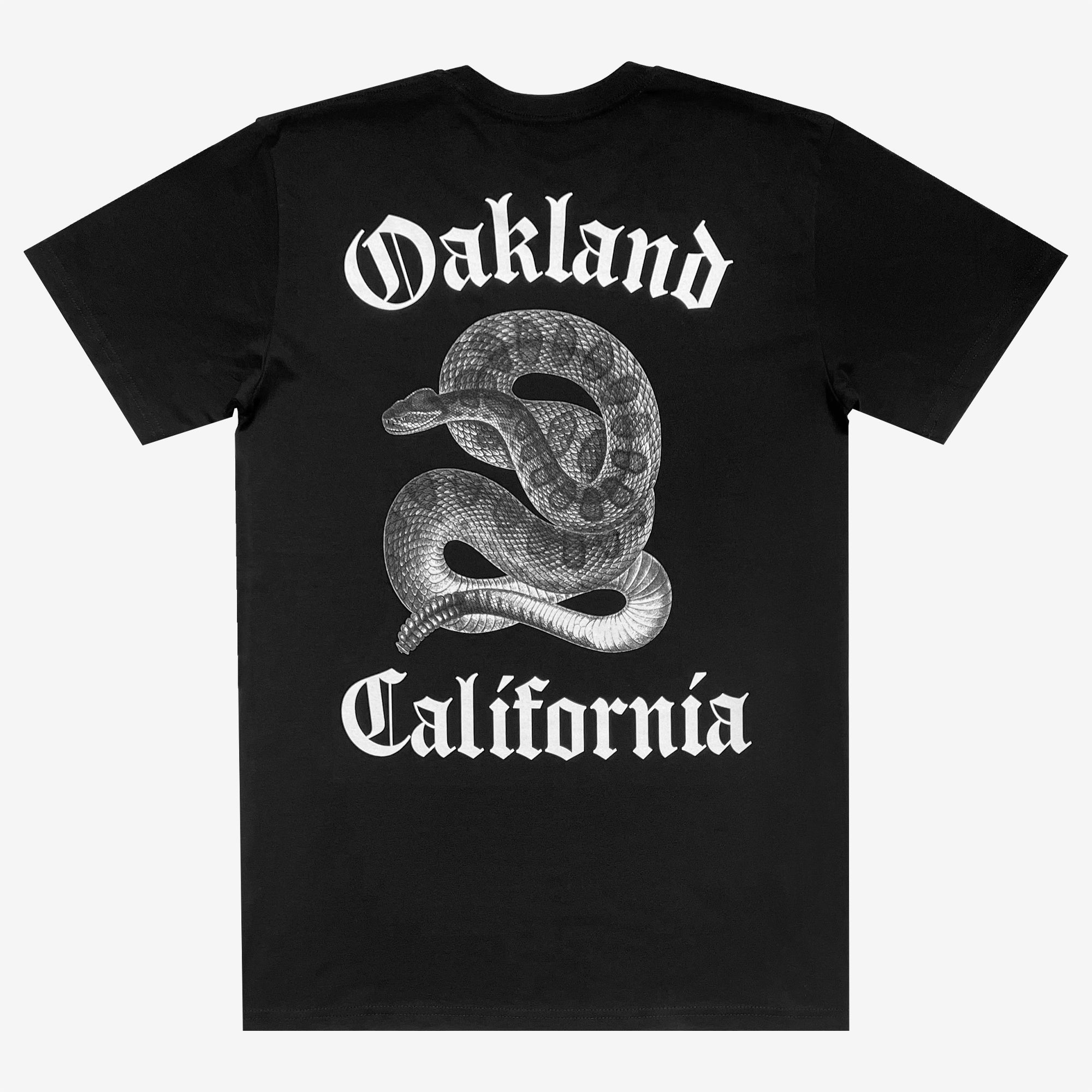 The Sistrurus Tee by Oaklandish is a black T-shirt adorned with a coiled, venomous snake graphic on the back. Above the snake, the word "Oakland" is prominently displayed, and below it reads "California," both in a bold Gothic font. Made from 100% cotton, this classic fit T-shirt design is in white, providing a striking contrast against the black fabric.