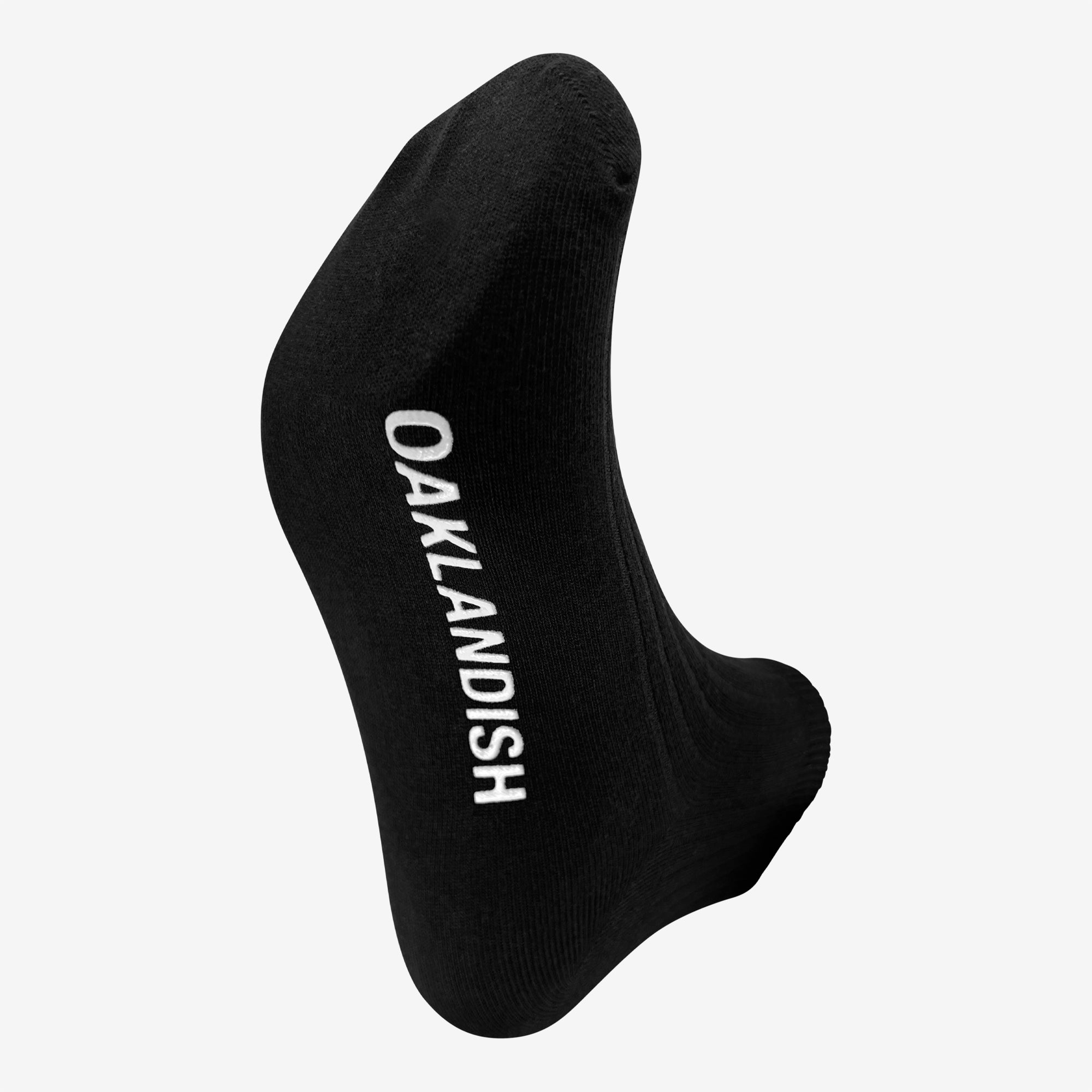 A single Grip Low Crew Sock by Oaklandish is displayed with the foot area facing forward. The sock features the word "OAKLANDISH" written in white capital letters along its sole. The plain white background perfectly highlights the Oaklandish sock.