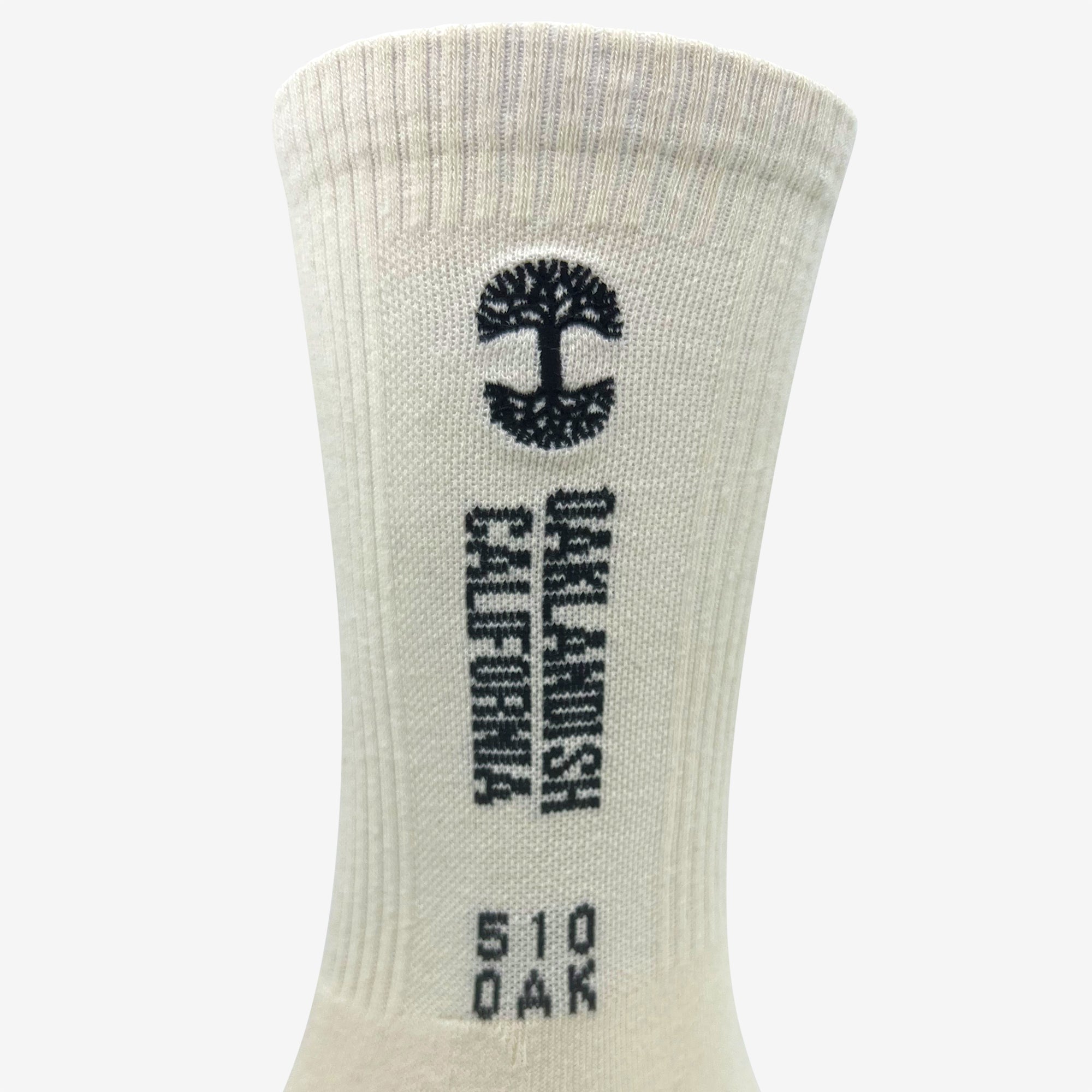 Close-up of a beige Oaklandish Utility Sock featuring several designs and text. Near the top, there is a black stylized tree logo. Below the logo, "SAN FRANCISCO" is printed vertically, accompanied by "CALIFORNIA" on the side. At the bottom, "510 OAK" is printed in a smaller font. Made from a cotton-polyester-spandex blend; one size fits all.