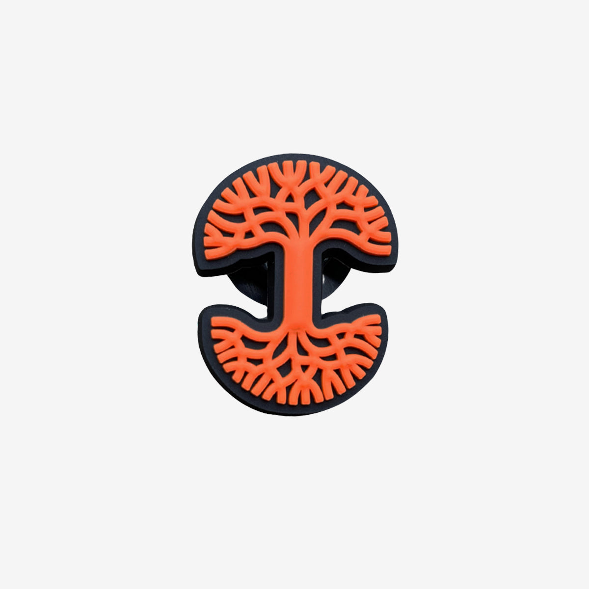 The Oaklandish Logo Charm by Oaklandish is a round, black button featuring an embossed design of a stylized tree in bright orange. The tree showcases intricate branching patterns with smooth curves and symmetry. This shoe charm, made of soft PVC, has a plain white background that accentuates the striking contrast between the black button and the vibrant orange tree design.